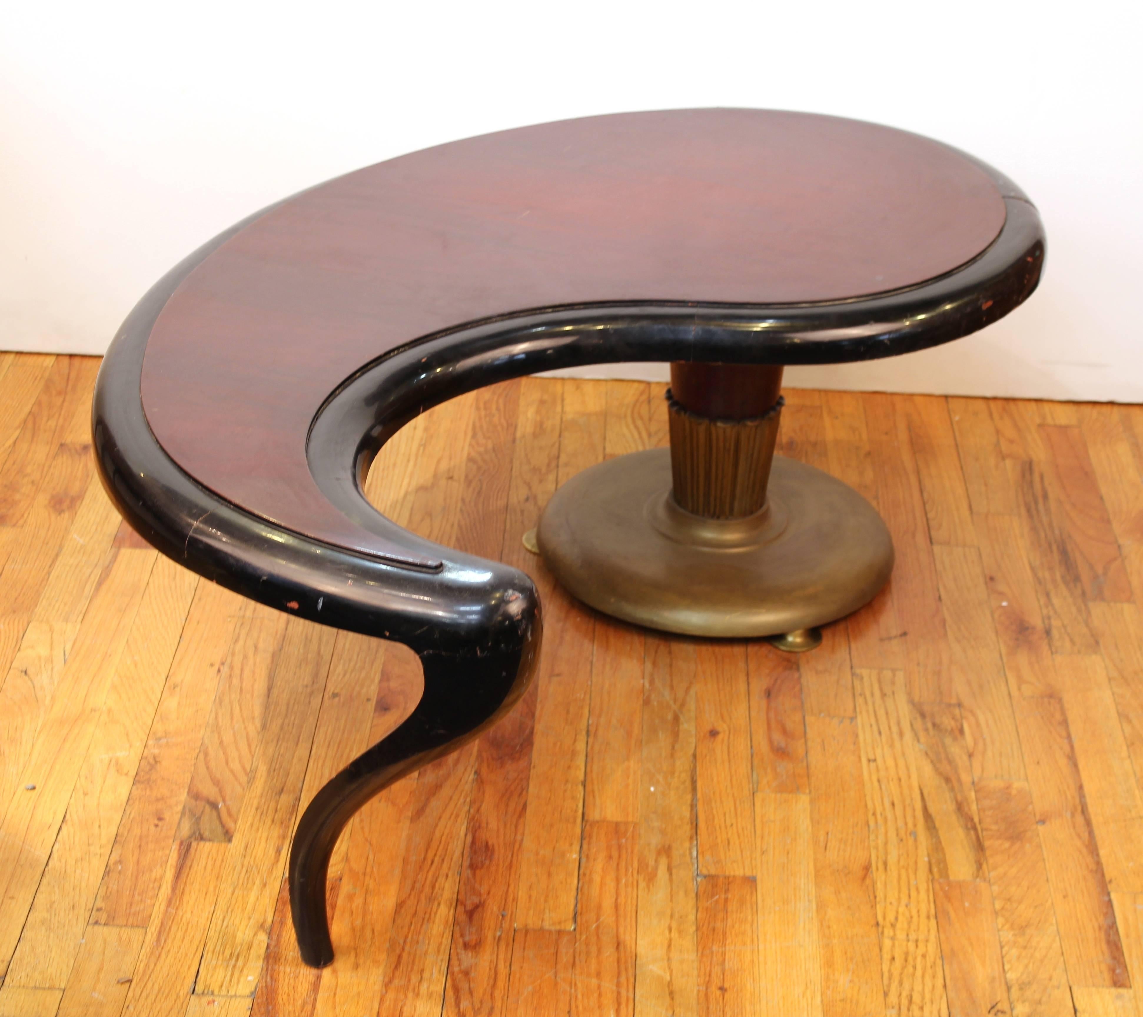 An American ebonized paisley-shaped coffee or cocktail table with one column-shaped leg and one curved leg. Produced in the 1950s by John Tavis, with triangular metal 'John Tavis Original' label on bottom. The piece is in original vintage condition