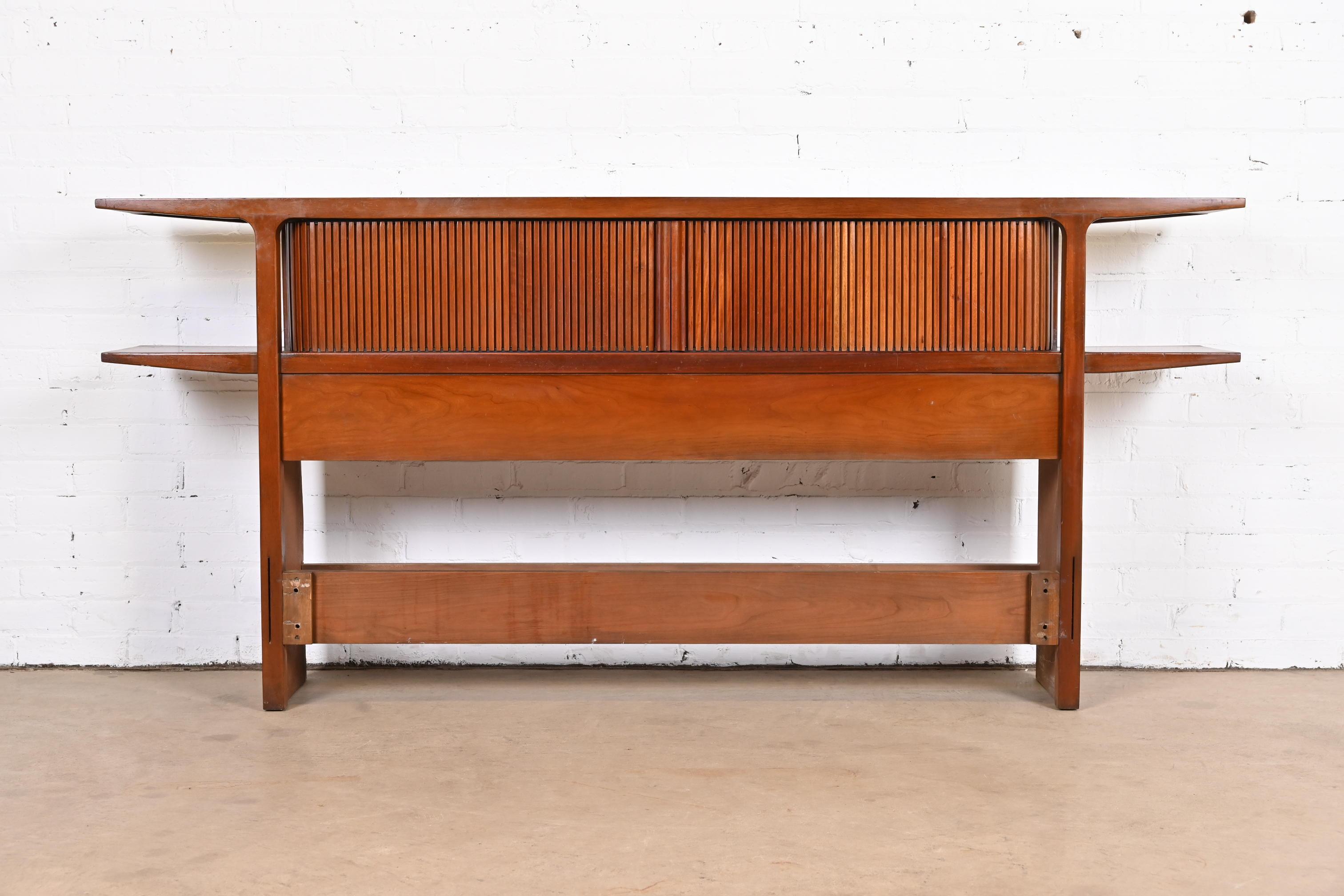 A stylish Mid-Century Modern sculpted walnut tambour door bookcase headboard with unique built-in floating cantilevered bedside tables

By John Van Koert for Drexel, 
