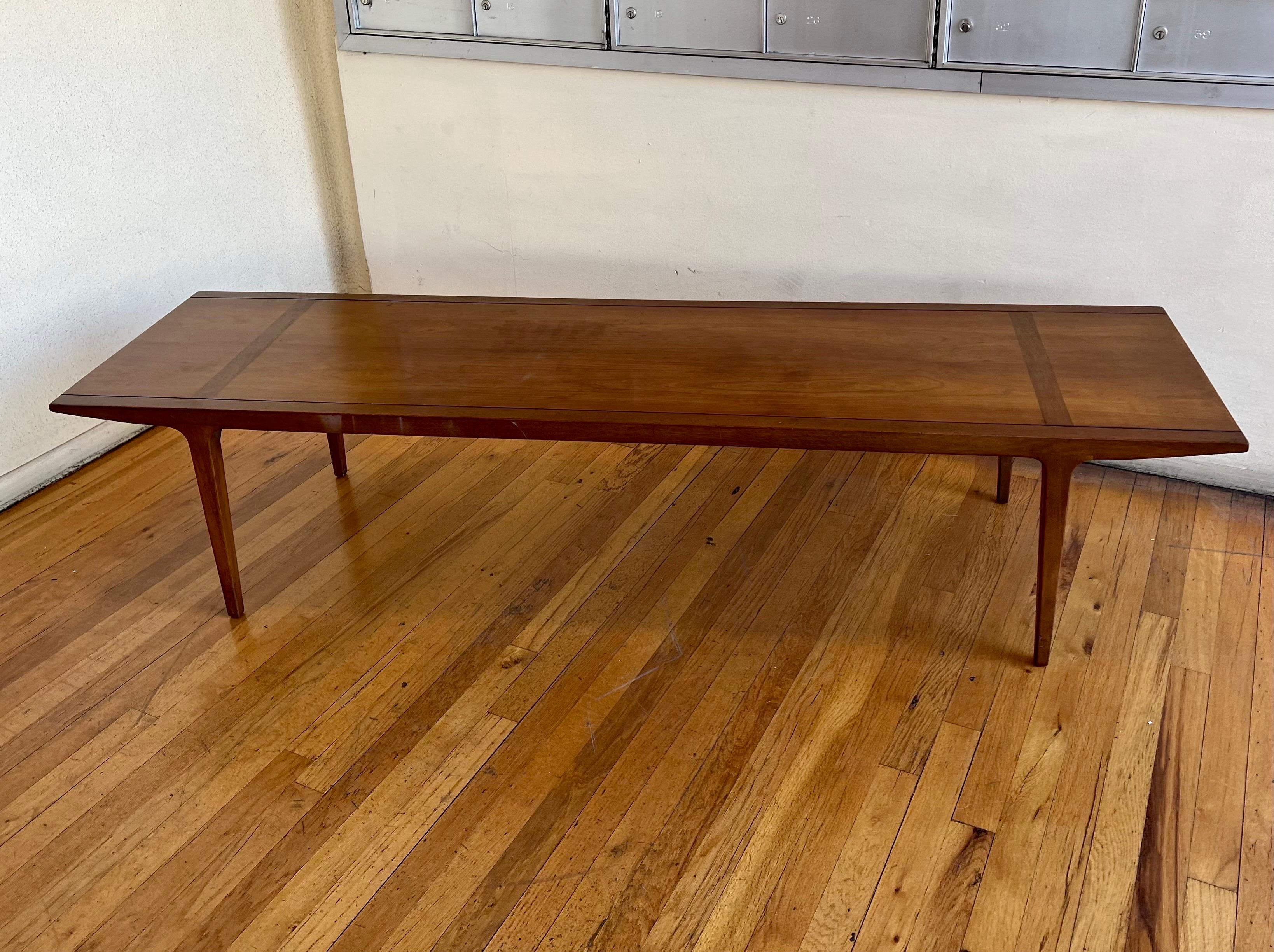 Mid-Century Modern coffee table was designed by American designer John Van Koert and manufactured by Drexel in the United States in the 1950s. Made of walnut wood, this coffee table’s gentle curves, clean lines, and four smooth tapered legs make
