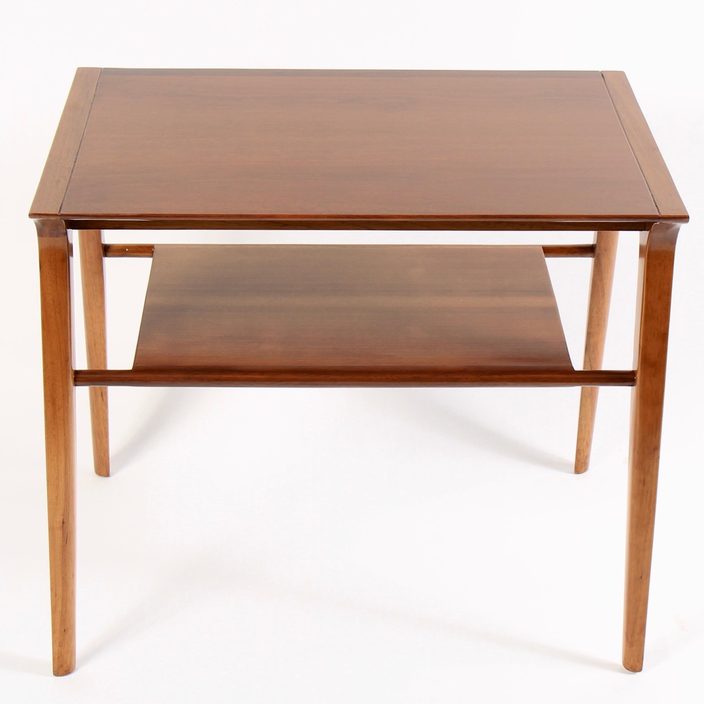 Mid-Century Modern side table designed by American designer John Van Koert and manufactured by Drexel in the United States, circa 1950s. With a solid and stabile walnut wood frame and two tapered shelves, this end/side table illustrates a stylish