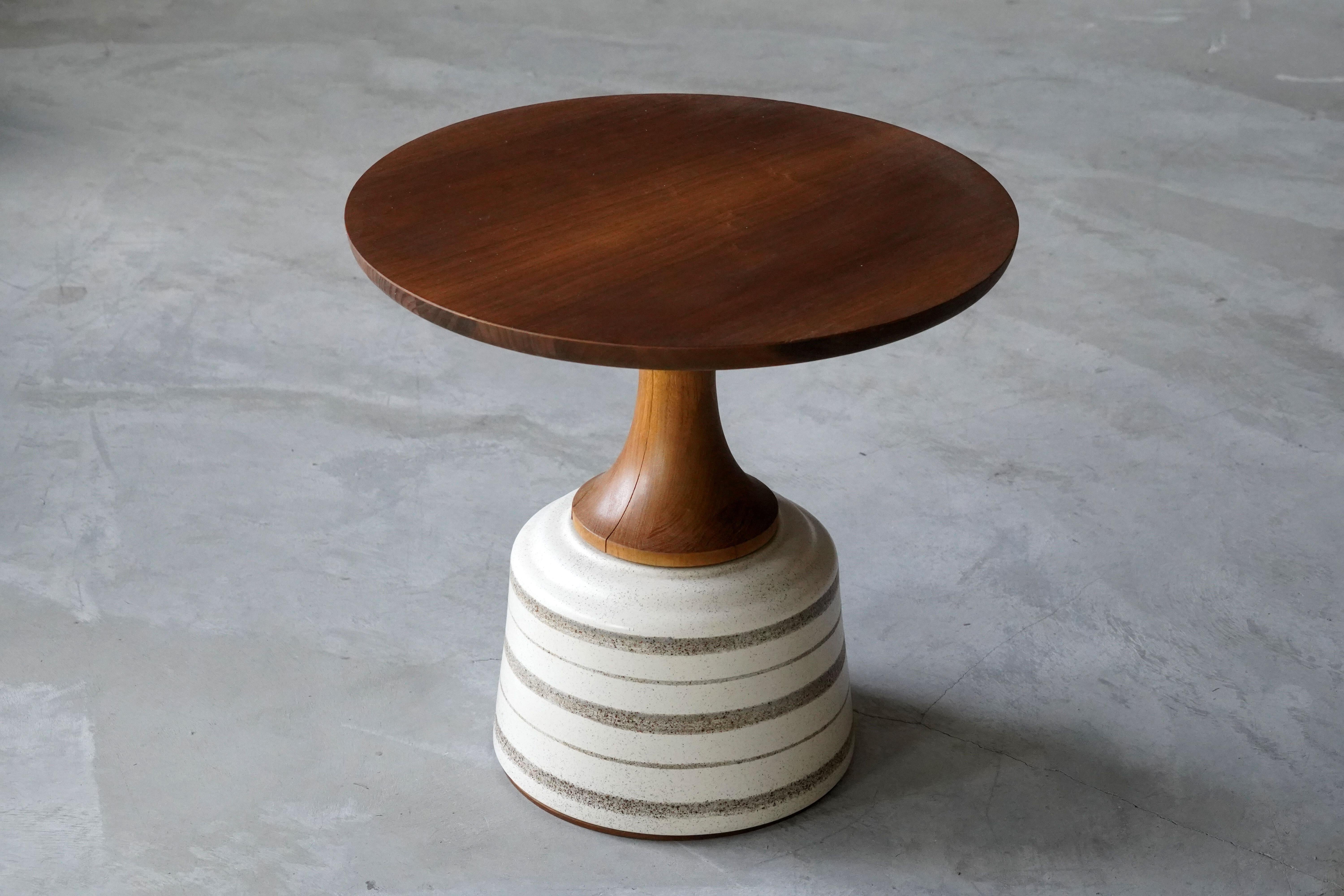 A side table or occasional table, designed by John Van Koert and produced by Drexel Furniture Company, North Carolina, America. 

Finely carved cherrywood tops are mounted atop the glazed ceramic bases. 

Other designers of the period include