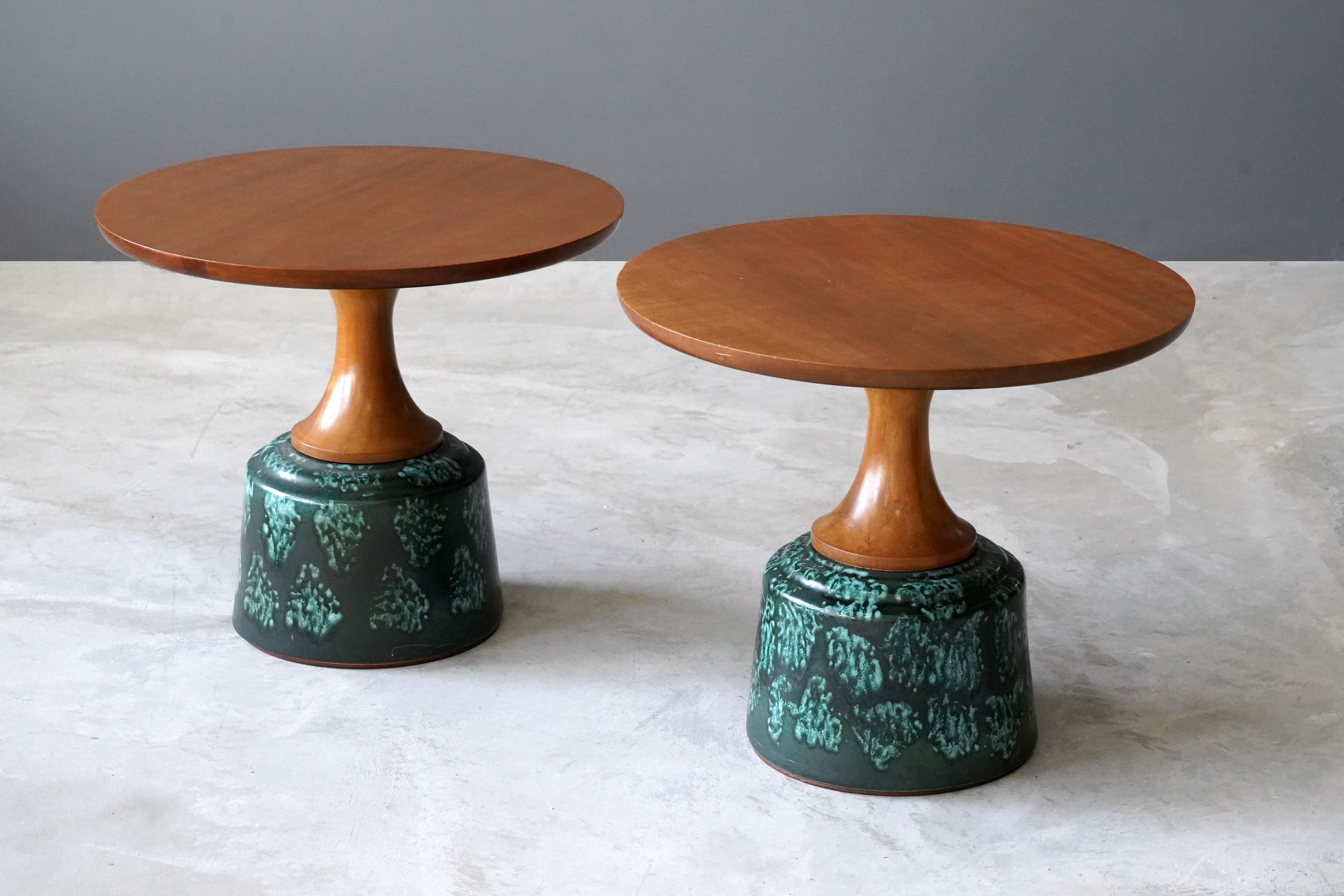 A pair of side table or occasional tables, designed by John Van Koert and produced by Drexel Furniture Company, North Carolina, America. 

Finely carved cherrywood tops are mounted atop the glazed ceramic bases. 

Other designers of the period
