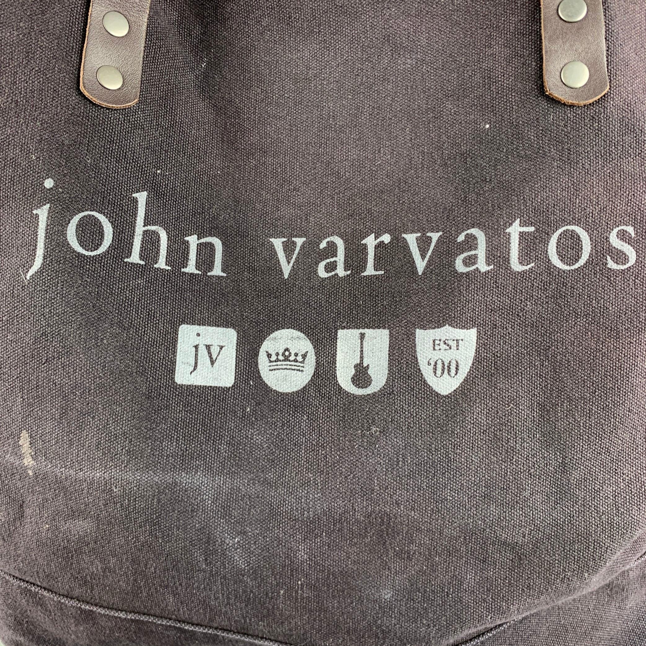 JOHN VARVATOS tote bag comes in a brown canvas details featuring a tote style, brown leather handles, and inner slots. Made in USA.Very Good Pre-Owned Condition. Signs of wear. 

Measurements: 
  Length: 22.5 inches Width: 9inches Height: 12.5
