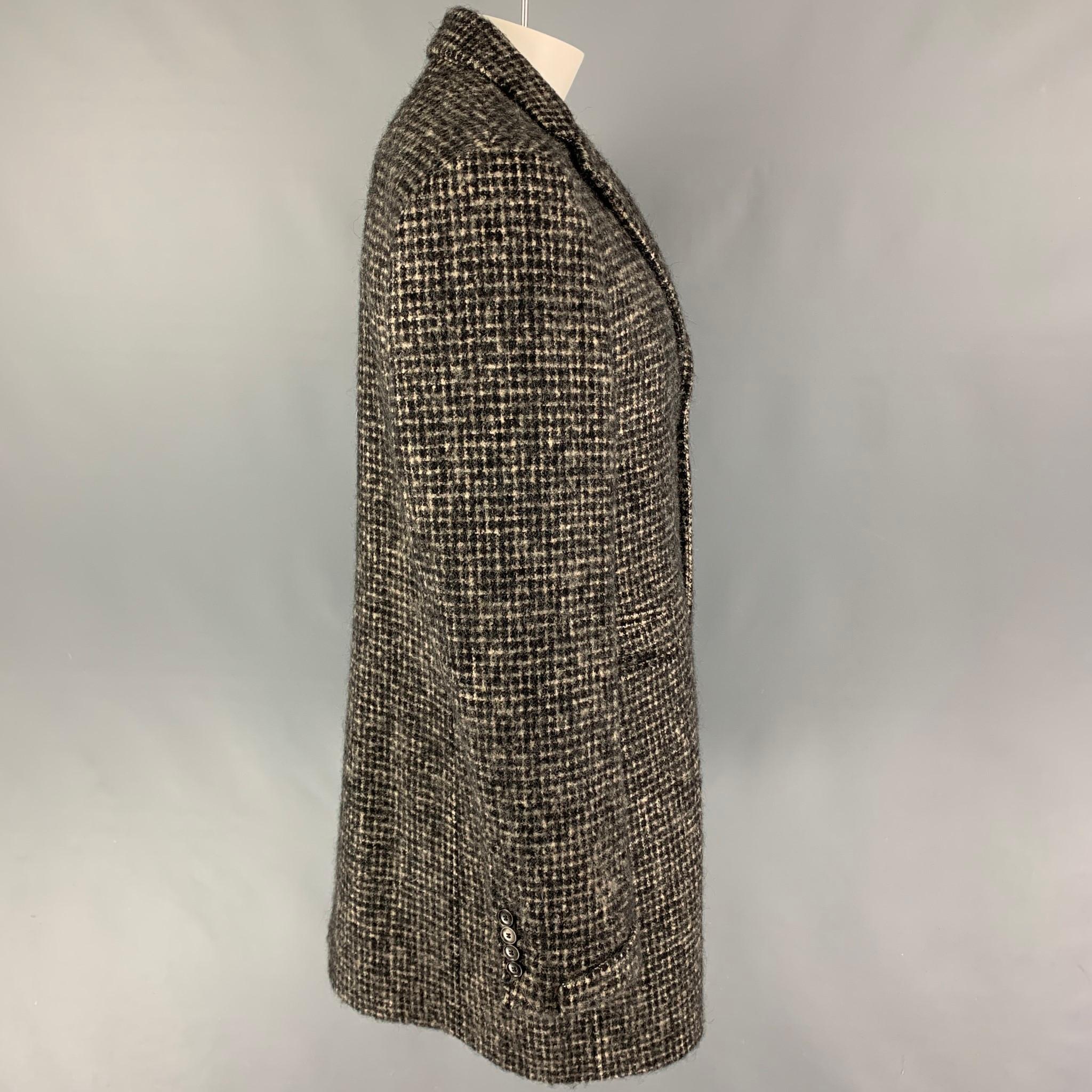 JOHN VARVATOS 'Limited Edition' coat comes in a black & cream checkered wool blend with a full liner featuring a notch lapel, slit pockets, single back vent, and a buttoned closure. Made in Italy. 

Very Good Pre-Owned Condition.
Marked: 52
Original
