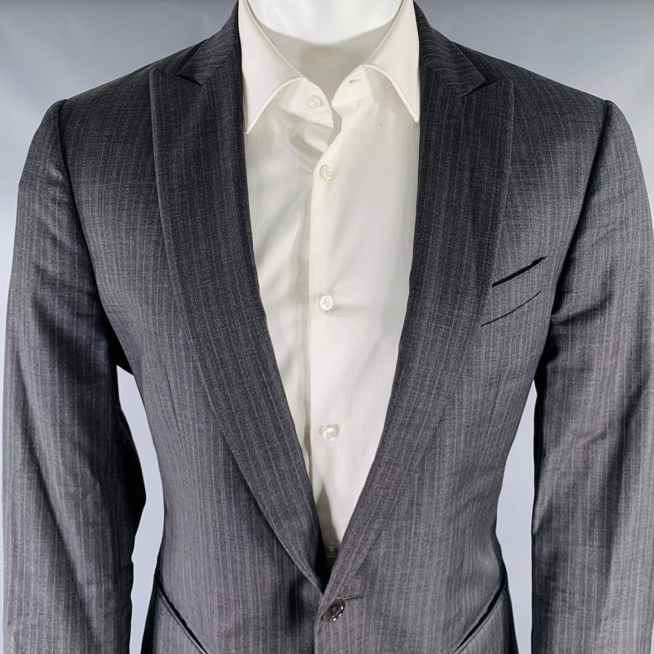 Abito John Varvatos
in lana vergine a righe grigio antracite con fodera integrale e comprende un cappotto sportivo monopetto a un bottone con bavero a punta e pantaloni piatti abbinati. 

Contrassegnato:   IT 50 

Misure: 
  -GiaccaSpalla: 17