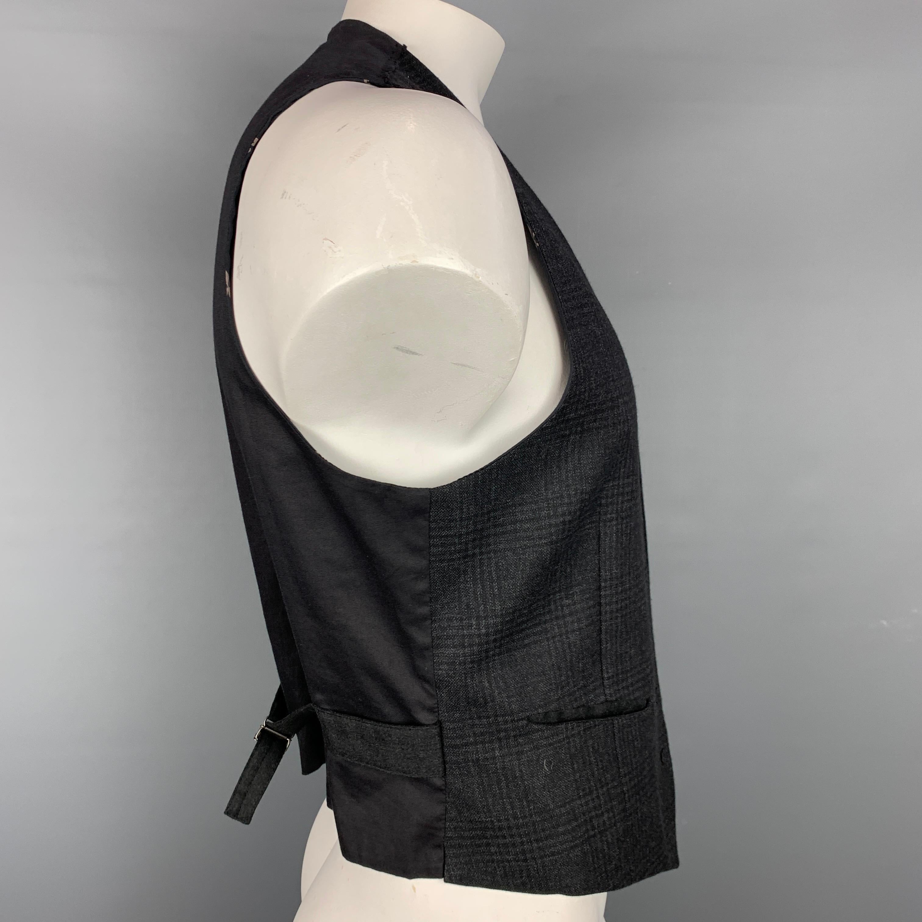 JOHN VARVATOS vest comes in a grey & black plaid wool featuring a double layer style, back belt, slit pockets, and a buttoned closure. Made in Italy.

Very Good Pre-Owned Condition.
Marked: 52

Measurements:

Shoulder: 14 in.
Chest: 40 in.
Length: