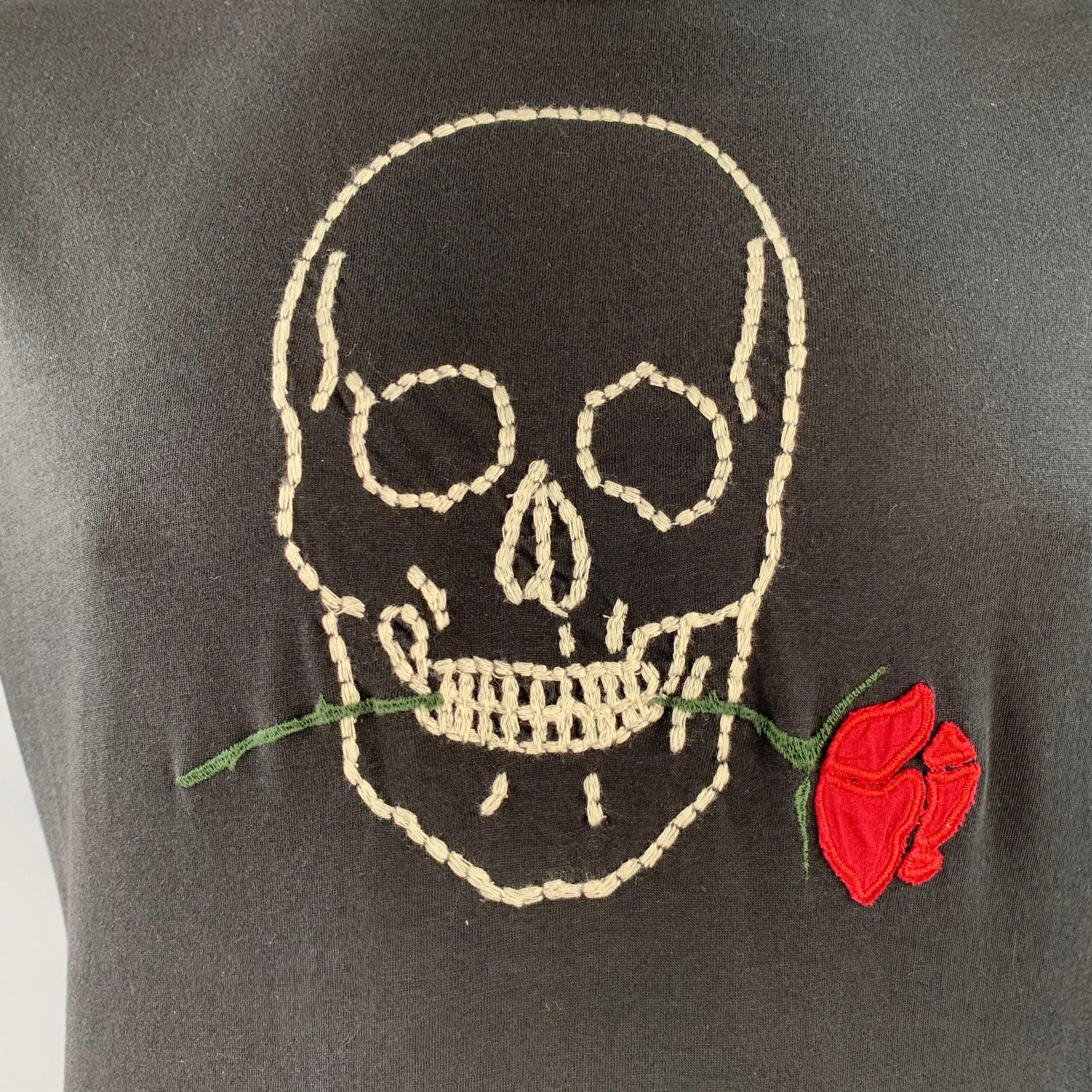 JOHN VARVATOS * T-shirt U.S.A.
en jersey de coton noir, avec une tête de mort brodée en blanc et rouge et une rose, et une encolure ras du cou.Très bon état d'occasion. Petite marque sur le côté. 

Marqué :   L 

Mesures : 
 
Épaule : 17.5 pouces