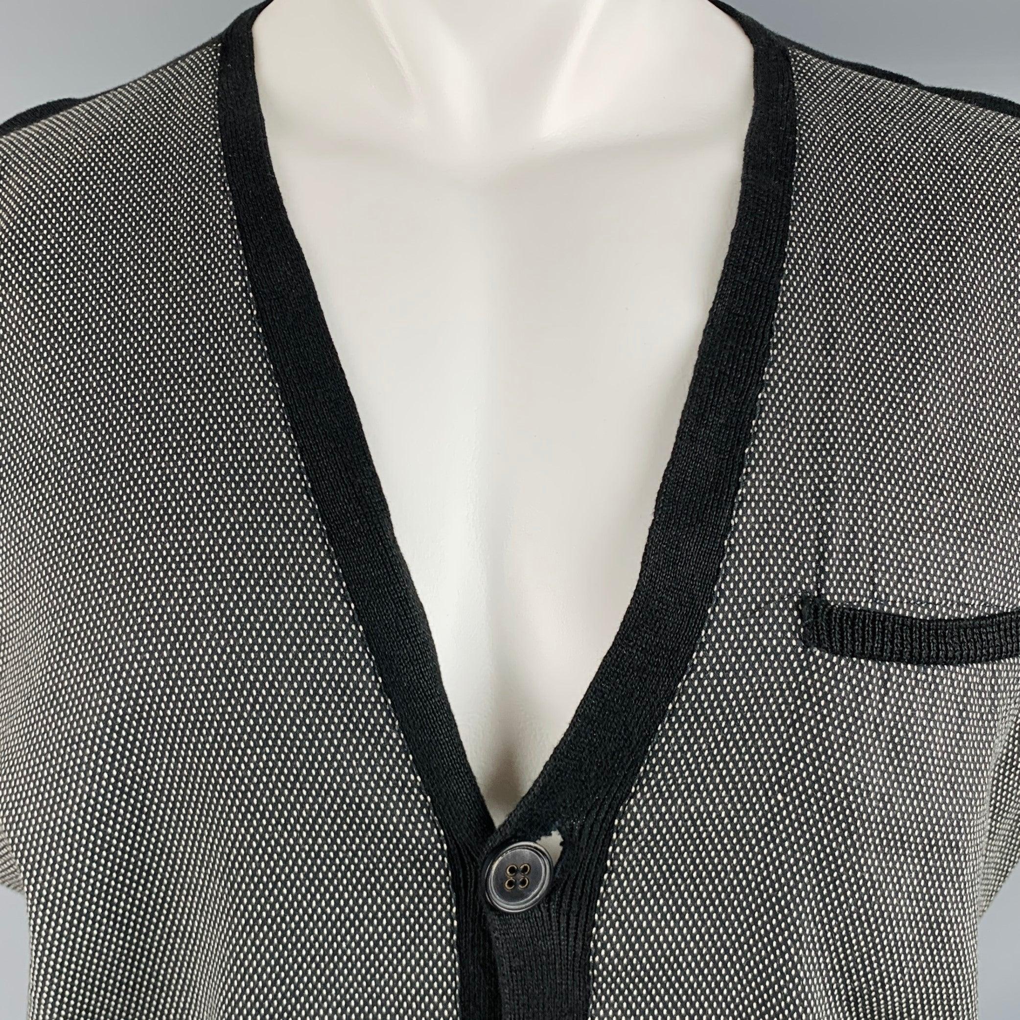 JOHN VARVATOS cardigan
in a black and white linen featuring nailhead pattern, extra long contrasting black knit sleeves, three pockets with contrasting black trim, and button closure.Very Good Pre-Owned Condition. Minor signs of wear. 

Marked:   M