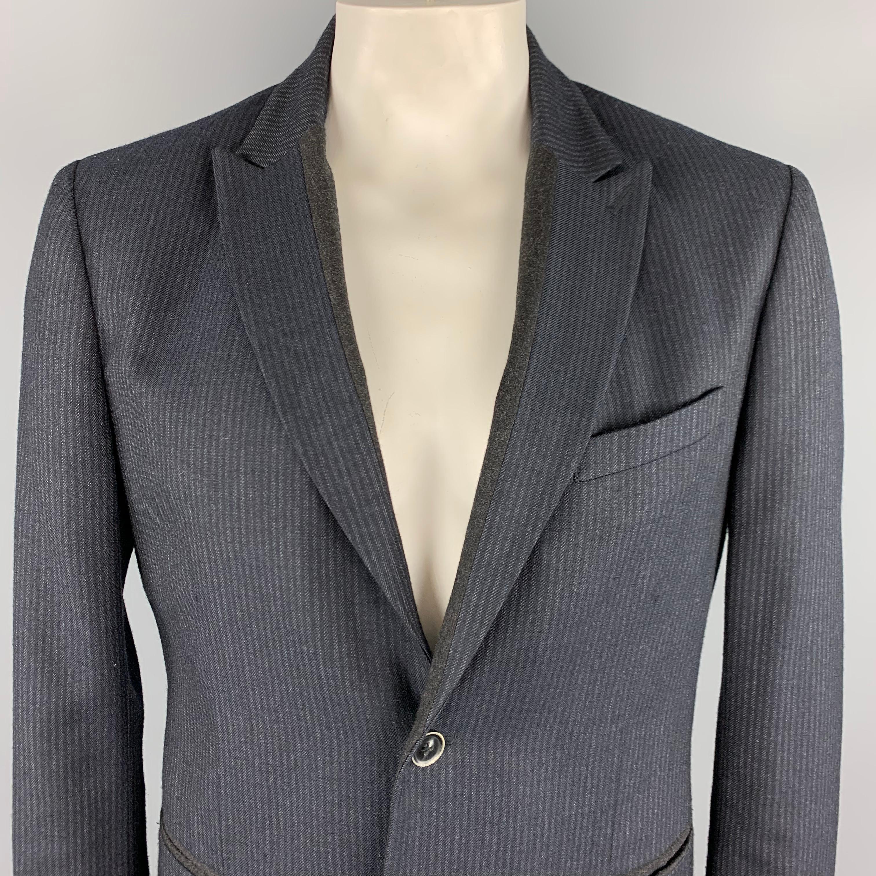 JOHN VARVATOS LUXE Sport Coat comes in a charcoal tone in a striped wool blend material, with a peak lapel, slit pockets, two buttons at closure, single breasted, single vent at back, buttoned cuffs, unlined.
 
Excellent Pre-Owned Condition.
Marked: