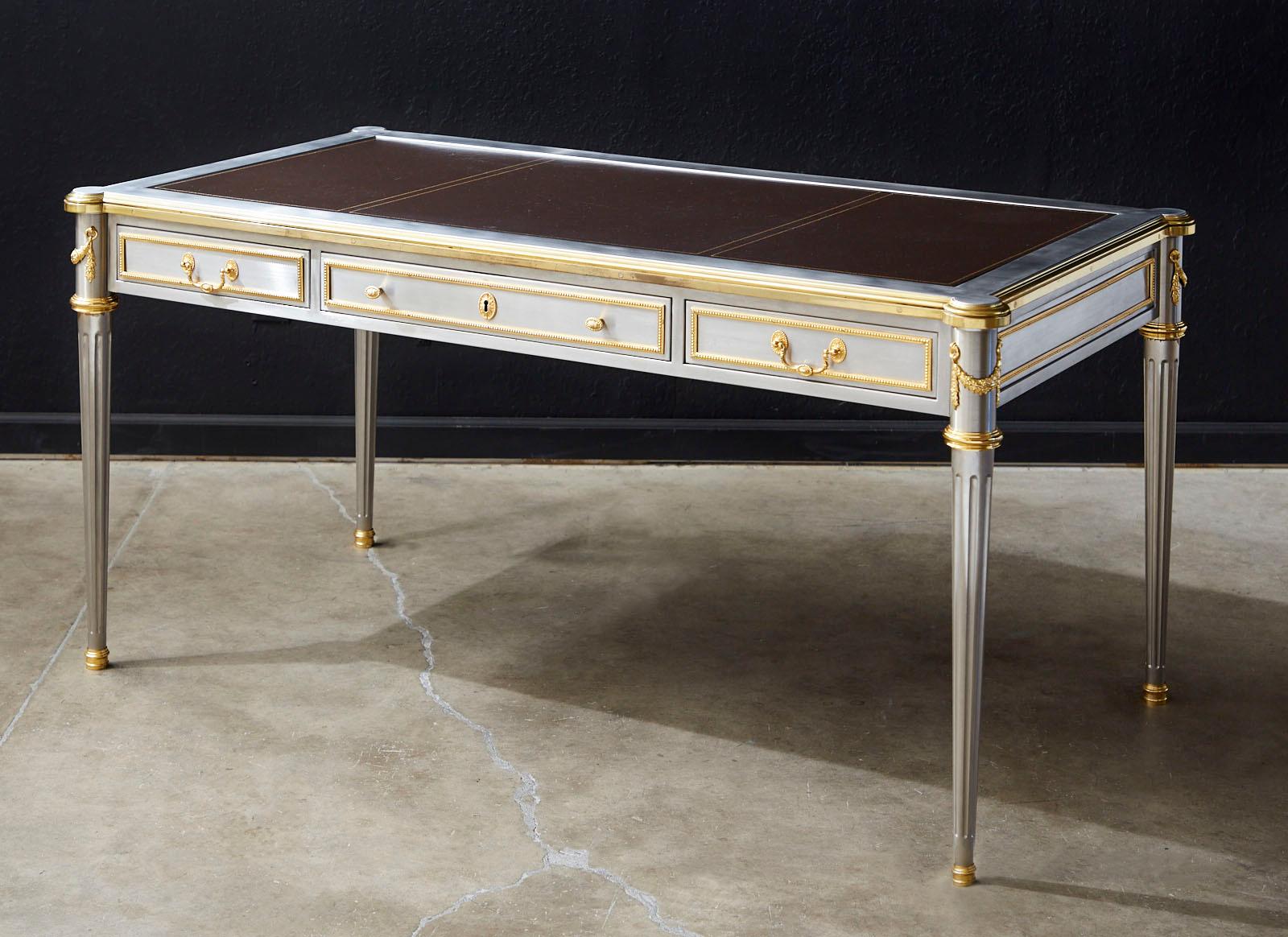 Opulent and rare 1960s stainless steel and bronze writing table, bureau plat desk designed by John Vesey (American 1924-1992). Made in the grand neoclassical French Louis XVI taste featuring gilt bronze trim and an iconic profile with elegant fluted