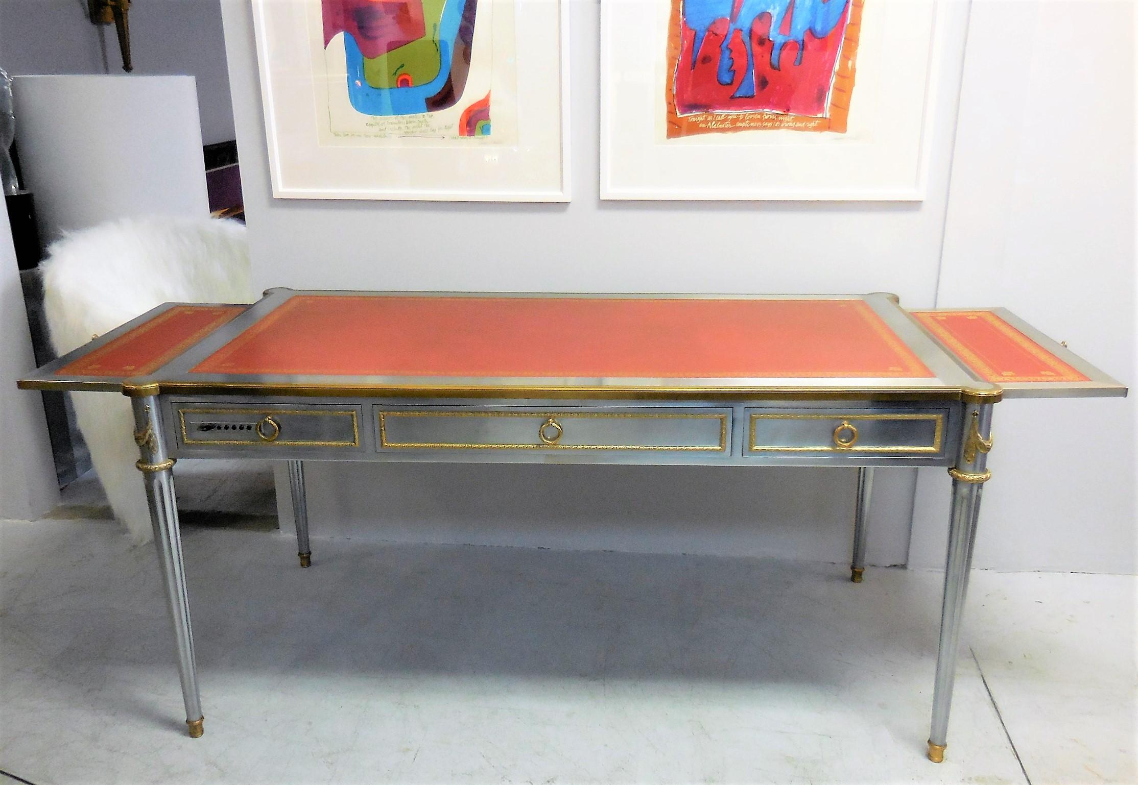 V-60 desk by John Vesey. A rare example of this very elusive desk. Solid stainless steel body with bronze doré mounts, hardware by P.E. Guerin and original gold embossed red leather top. The desk has three drawers lined in suede, including one with