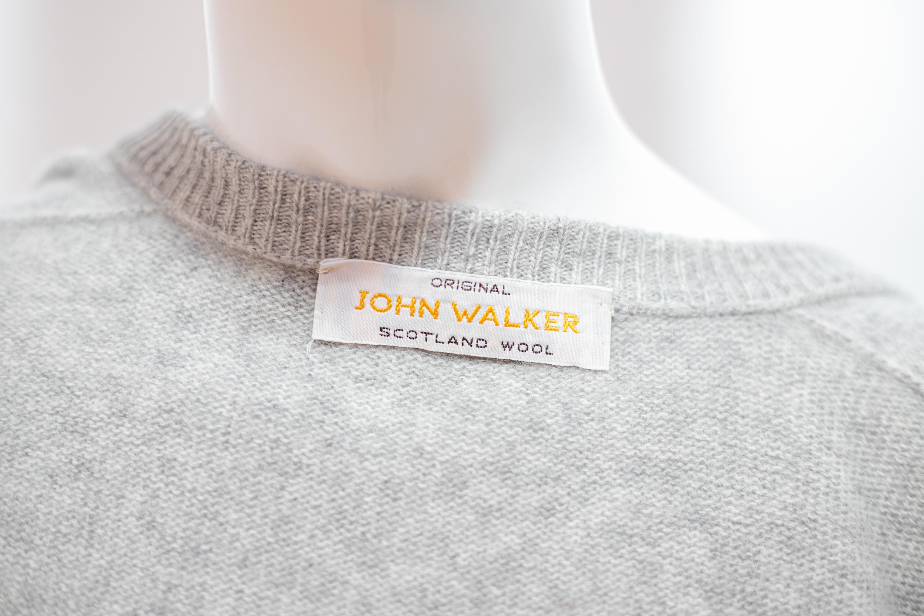 Schöner Wollpullover, entworfen von John Walker in den 1990er Jahren, hergestellt in Schottland.
Der Pullover ist ganz aus grauer schottischer Wolle gefertigt, mit langen Ärmeln und schmalen Bündchen.
Der Pullover hat einen klassischen U-förmigen
