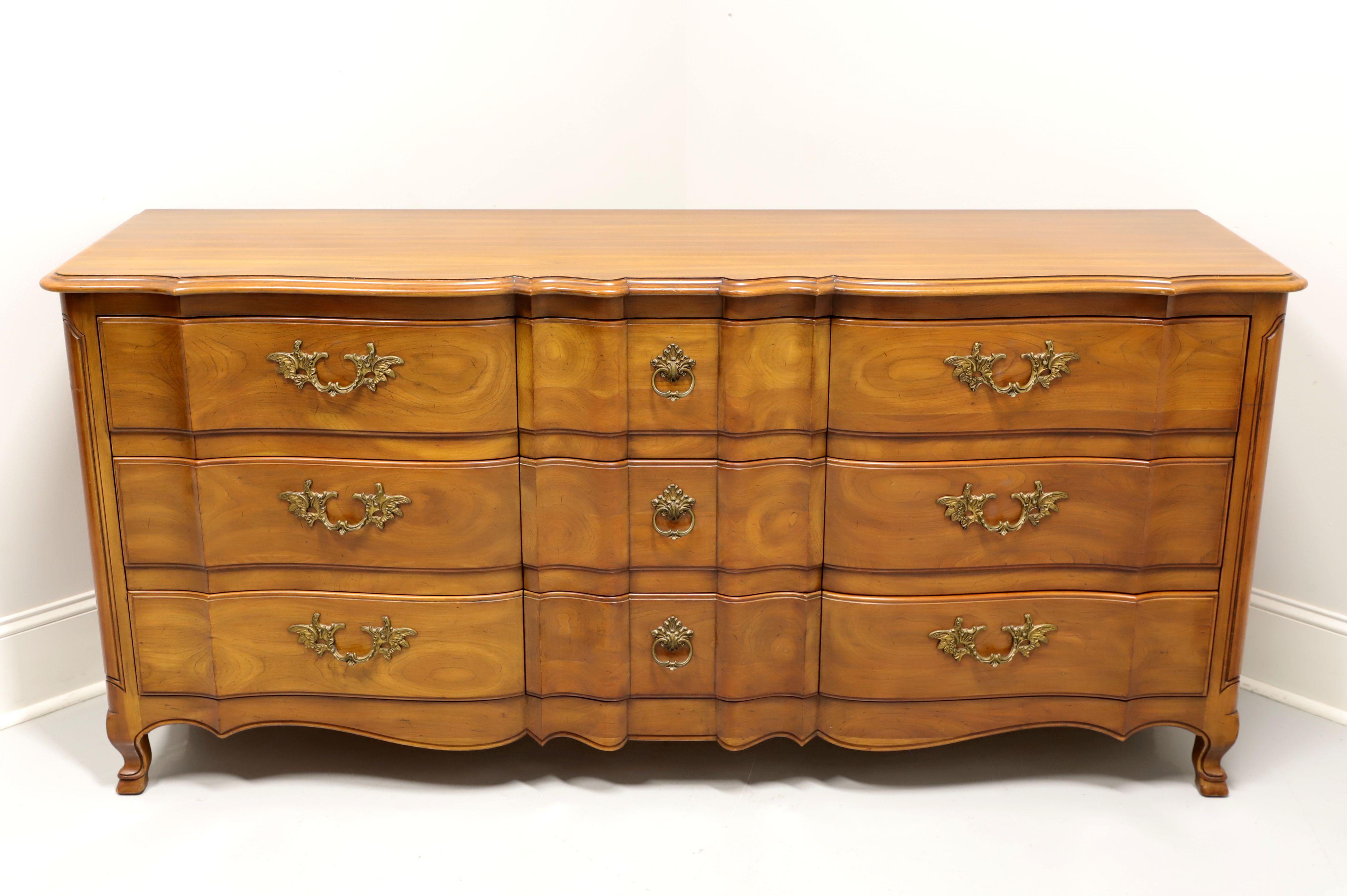 A French Country style nine drawer triple dresser by John Widdicomb, of Grand Rapids, Michigan, USA. Solid cherry with brass hardware, serpentine front, carved panels to front sides and scroll feet. Features nine drawers of dovetail construction