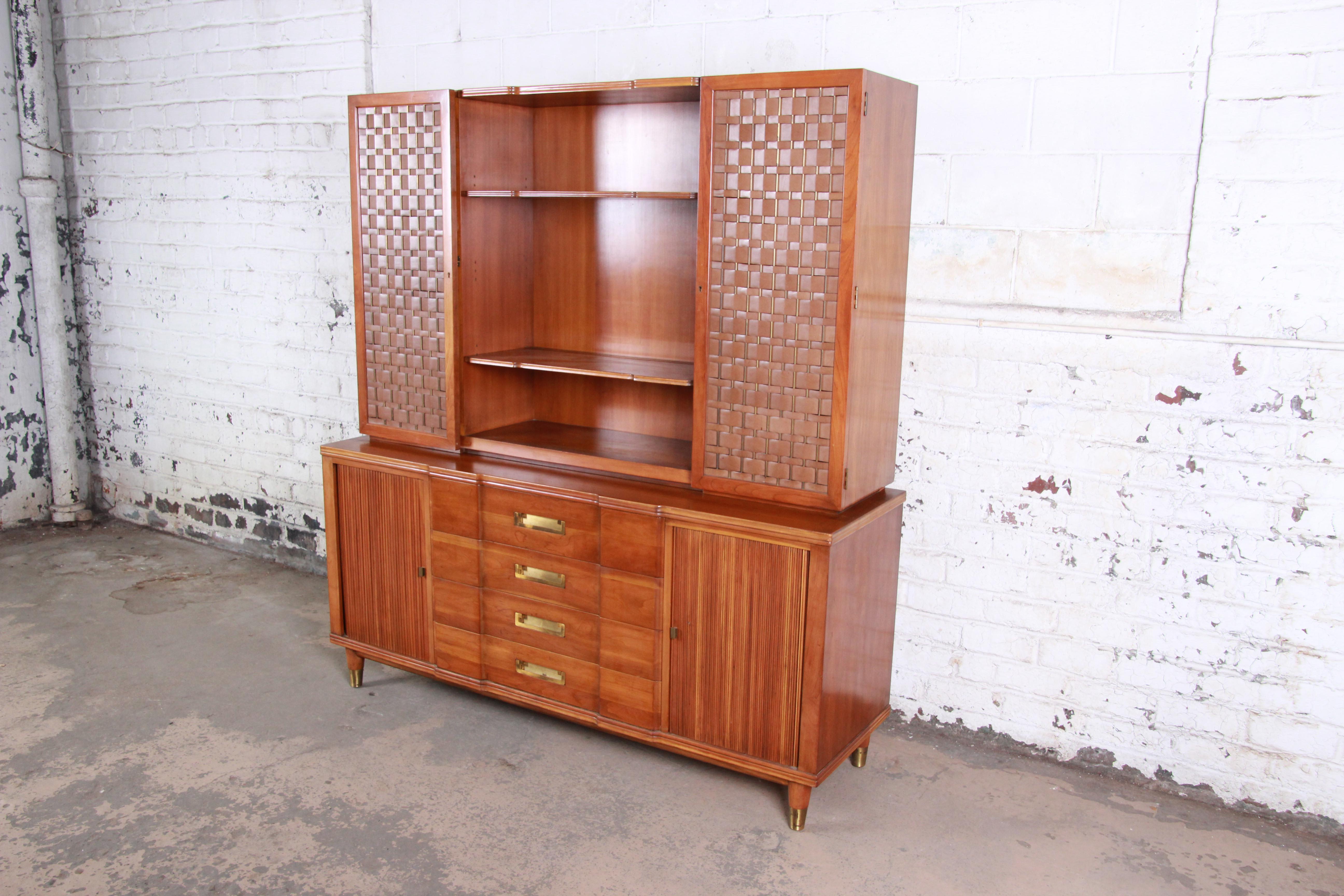 An exceptional Mid-Century Modern sideboard credenza with hutch top by John Widdicomb of Grand Rapids. The sideboard features solid cherrywood construction and a hutch top with unique woven leather and brass doors. It offers ample storage, the lower
