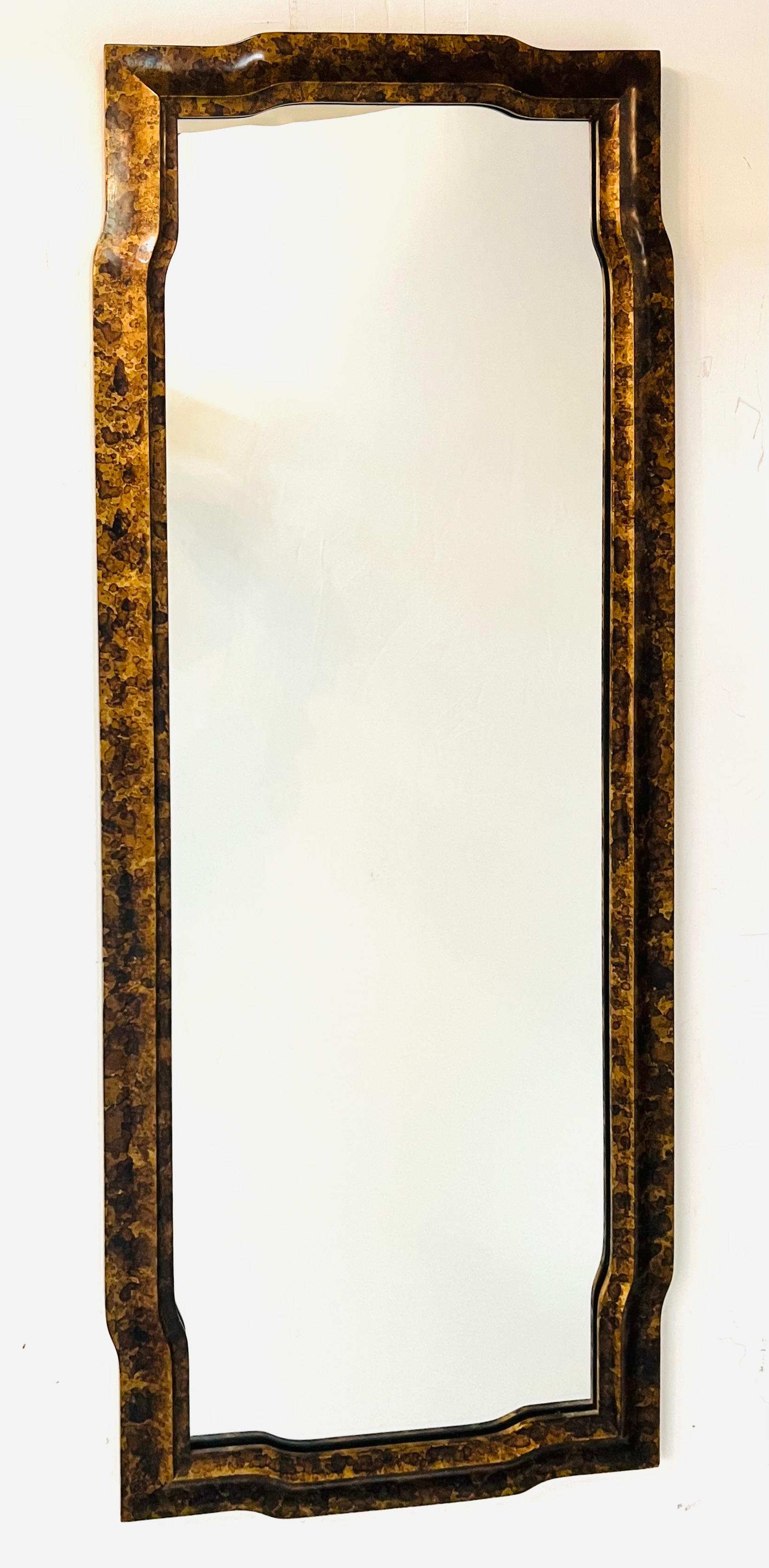 A Mid-Century Modern faux tortoise wall or console mirror designed by John Widdicomb for and manufactured by John Stuart. The beautiful mirror features fine curvy design and the faux tortoise in light and dark brown surface patten is gorgeous. The