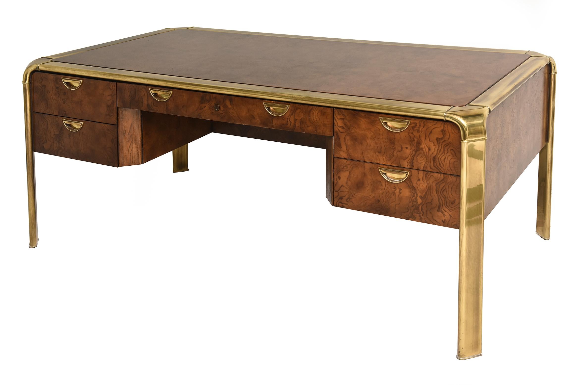This classic desk / executive desk by John Widdicomb for Mastercraft is burled wood and original brass hardware and legs. It is from the 1970s. It has 3 drawers; 2 on one side and 1 large deep drawer on the right. It has a front drawer in the