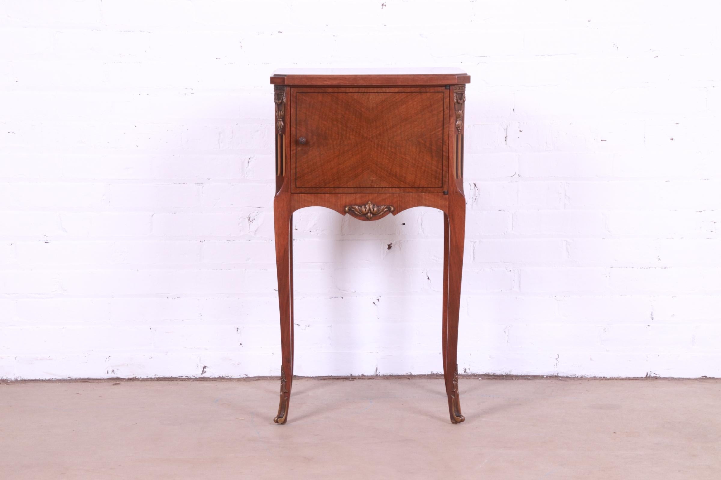 A gorgeous French Louis XV style nightstand or side table

By John Widdicomb

USA, Circa 1920s

Inlaid walnut, with carved giltwood details, and brass hardware and ormolu.

Measures: 16