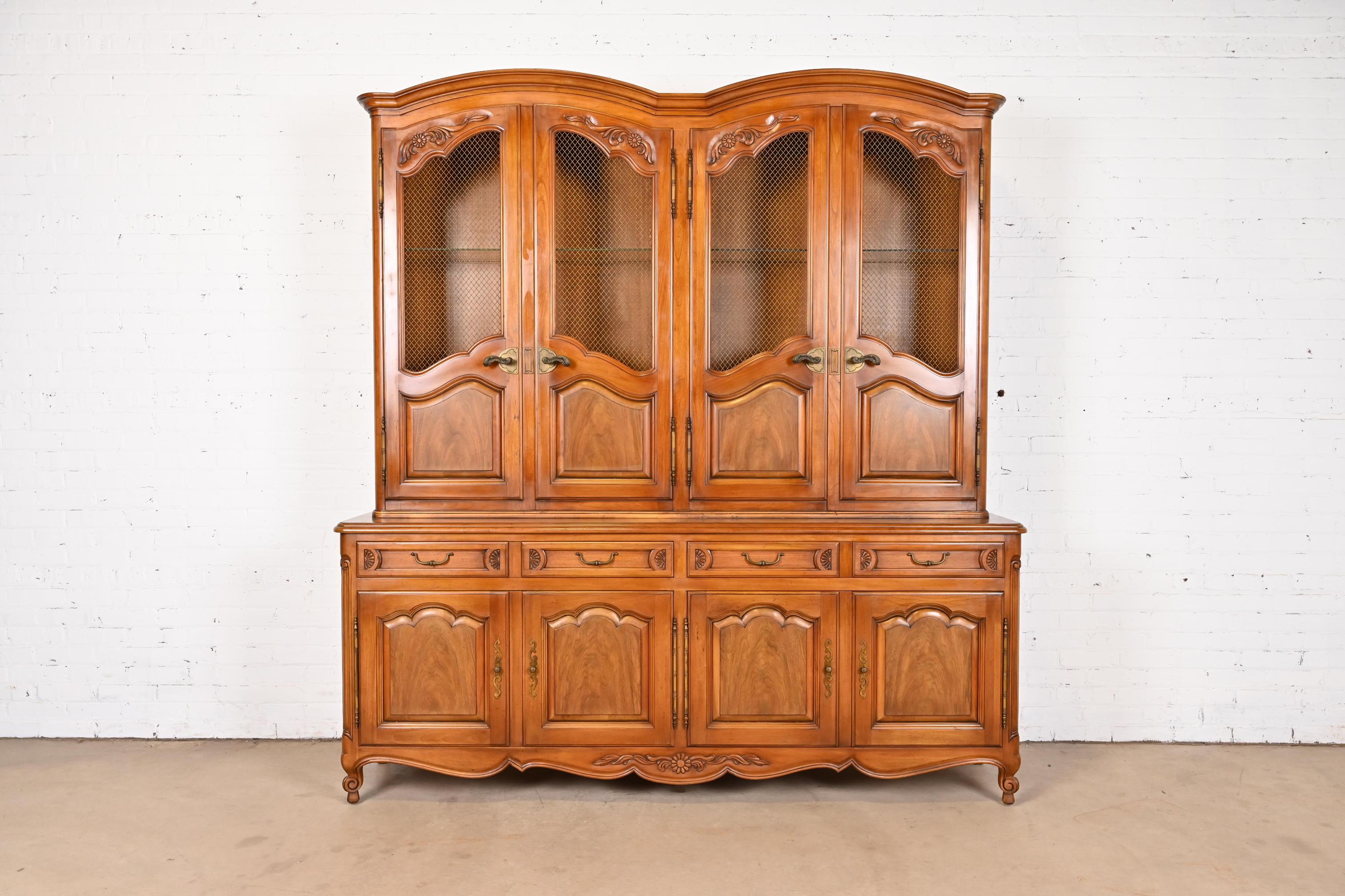 A gorgeous French Provincial Louis XV style two-piece lighted breakfront bookcase or dining cabinet

By John Widdicomb

USA, Circa 1960s

Beautiful carved solid cherry wood, with inset walnut panels, and original brass hardware.

Measures: 81.25