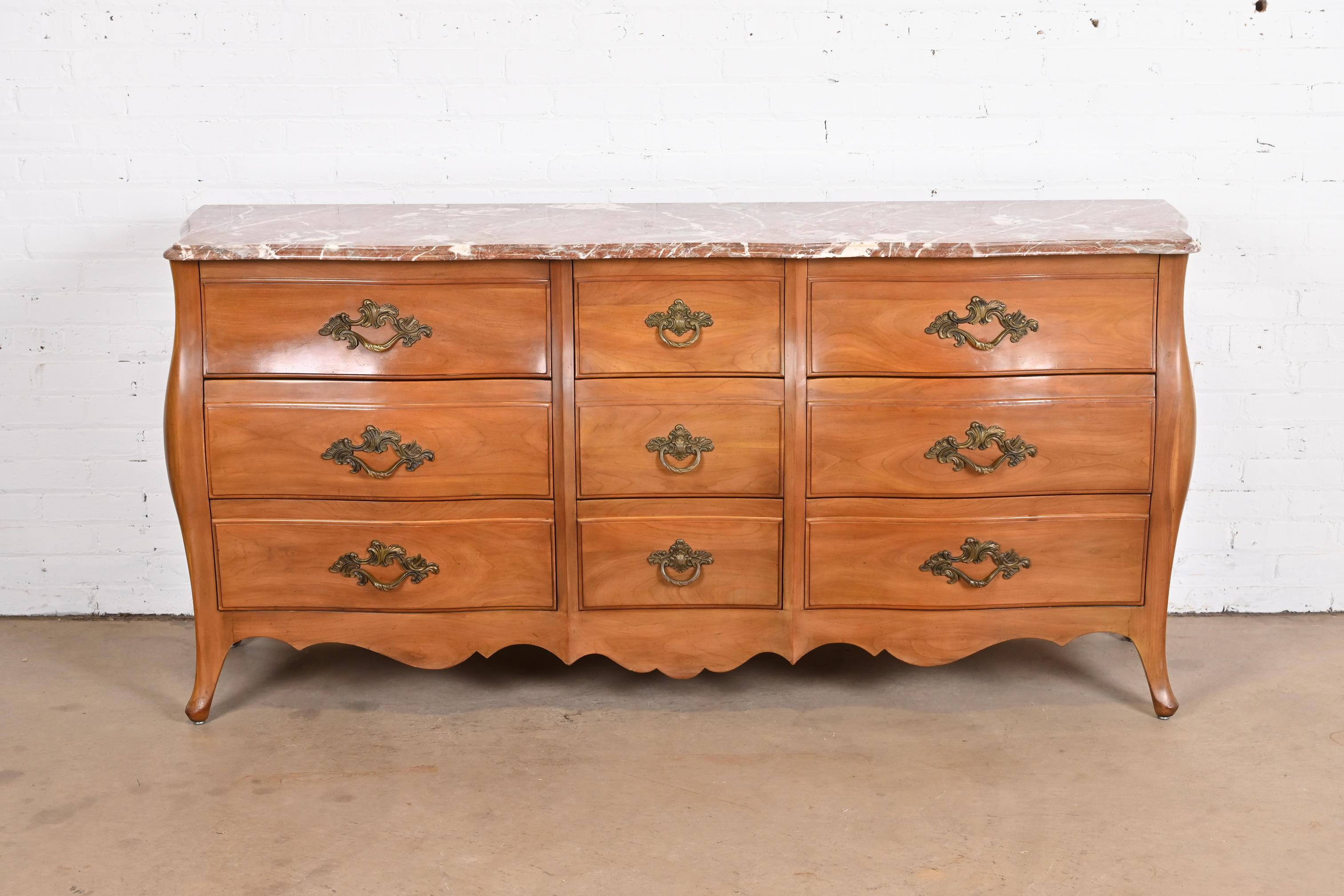 A gorgeous French Provincial Louis XV style bombe form nine-drawer triple dresser or credenza

By John Widdicomb

USA, circa 1950s

Carved solid cherry wood, with beautiful beveled Italian marble top, and original brass hardware.

Measures: