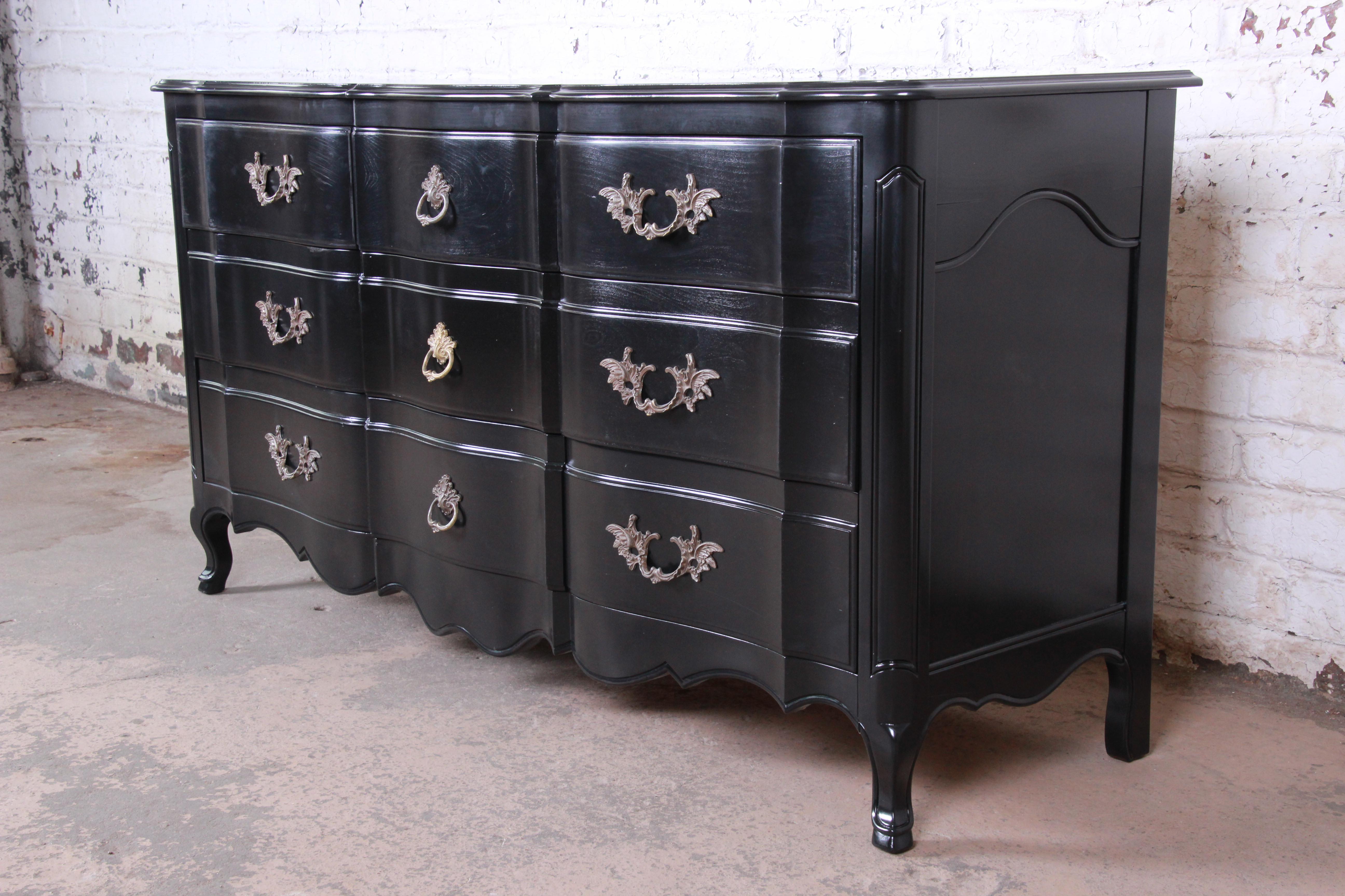 An exceptional French Provincial Louis XV style triple dresser or credenza by John Widdicomb. The dresser features beautiful walnut wood grain with a stunning newly ebonized finish. It has gorgeous carved wood details and original brass French