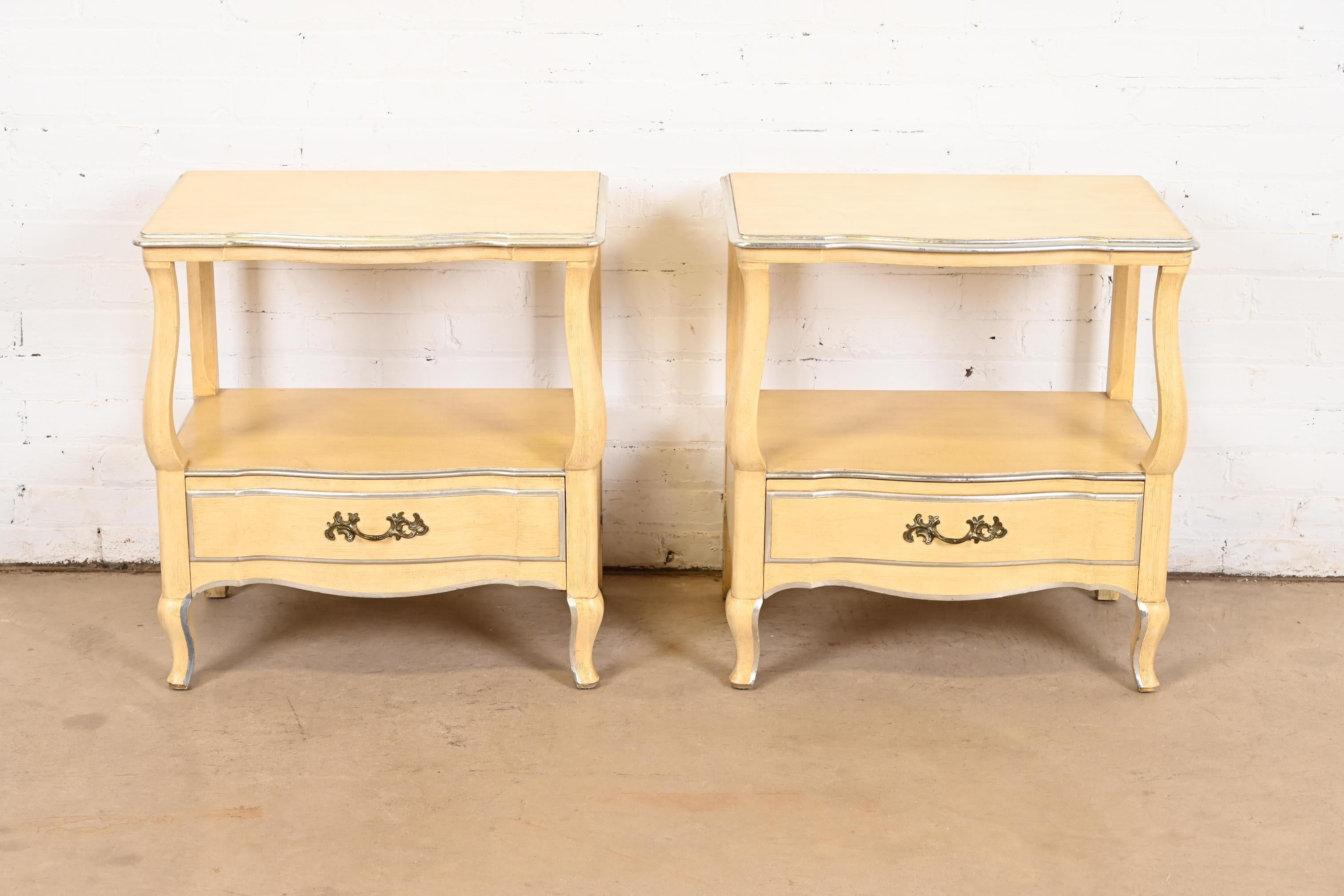 A gorgeous pair of French Rococo or French Provincial Louis XV style bedside tables or end tables

By John Widdicomb

USA, 1950s

Solid carved cherry wood, with original cream lacquered and silver gilt finish, and original brass hardware.

Each