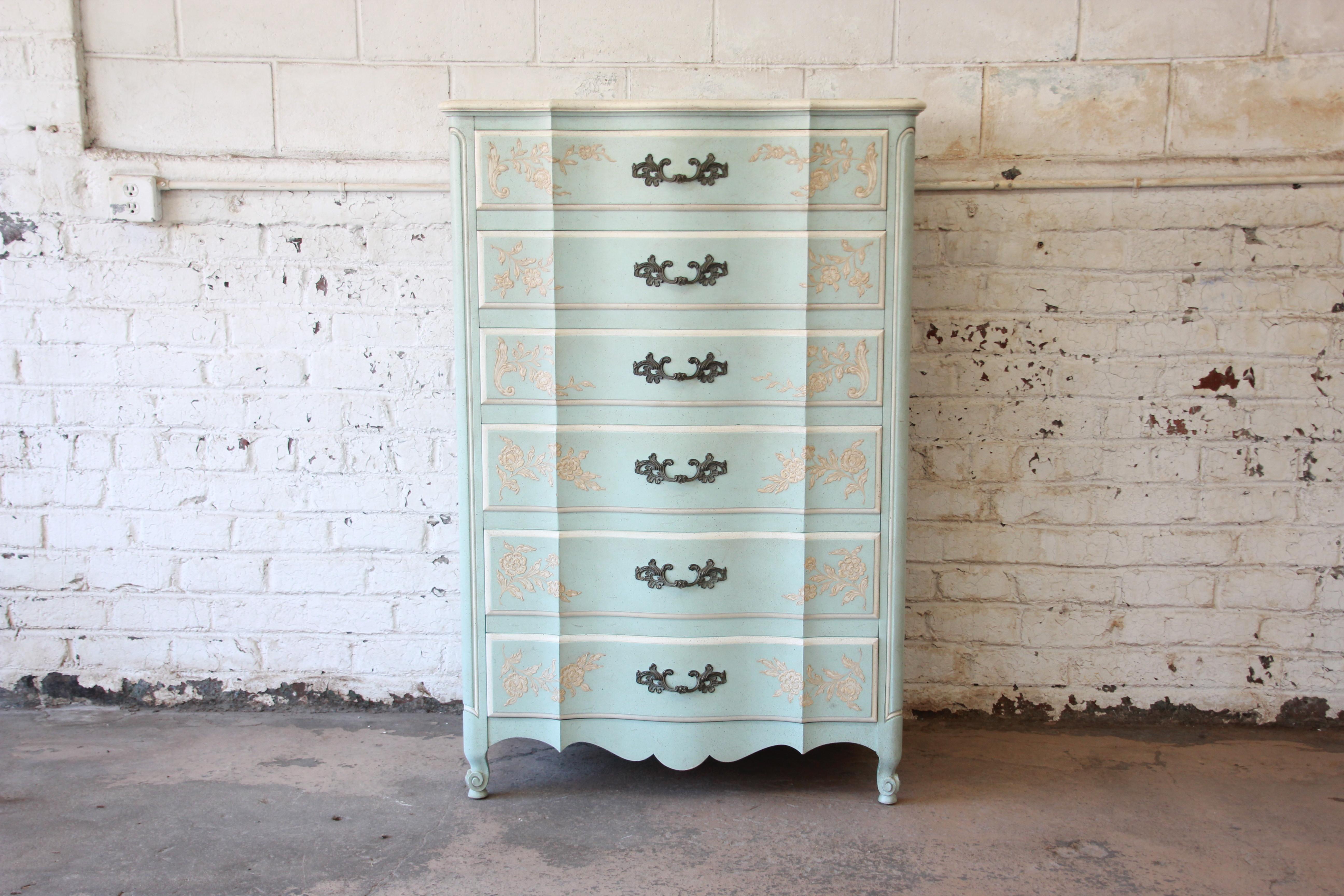 A gorgeous vintage French Provincial Louis XV style highboy dresser by John Widdicomb. The chest features the original light blue finish, with ivory trim and beautiful floral details. It offers ample room for storage, with six deep dovetailed