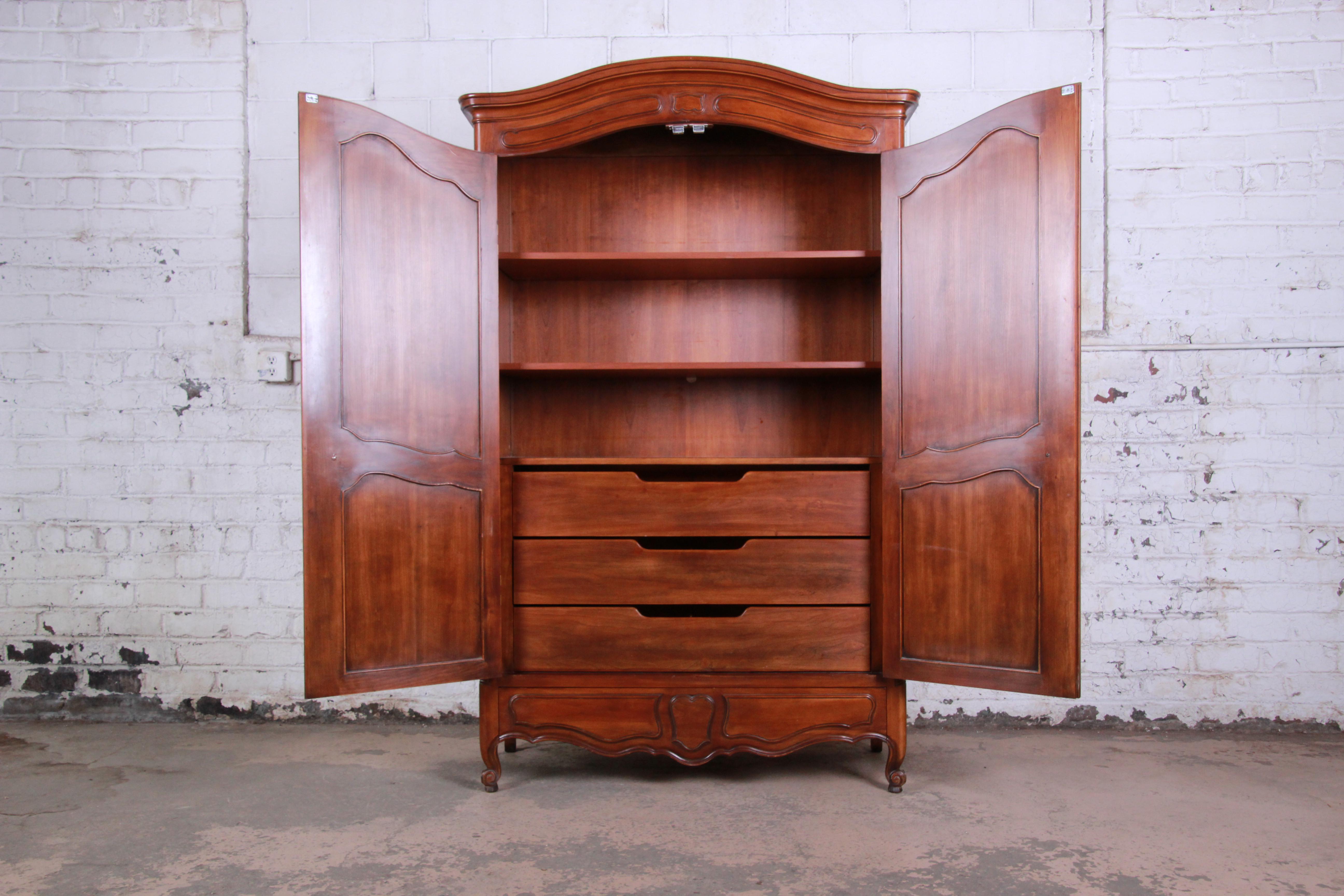 An exceptional French Provincial Louis XV style walnut armoire dresser by John Widdicomb of Grand Rapids. The armoire features beautiful walnut wood grain and nice French carved wood details. It offers ample storage, with two adjustable shelves and