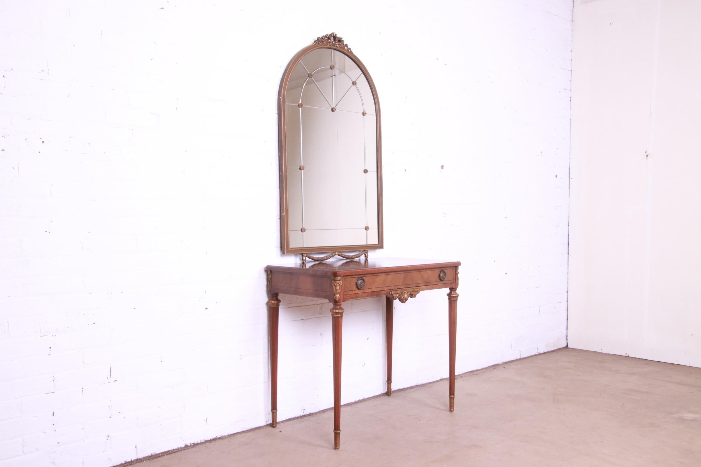 A gorgeous French Regency Louis XVI style vanity or writing desk with wall-hanging mirror

By John Widdicomb

USA, Circa 1920s

Inlaid walnut, with carved giltwood details, and original brass hardware.

Measures:
Desk - 33