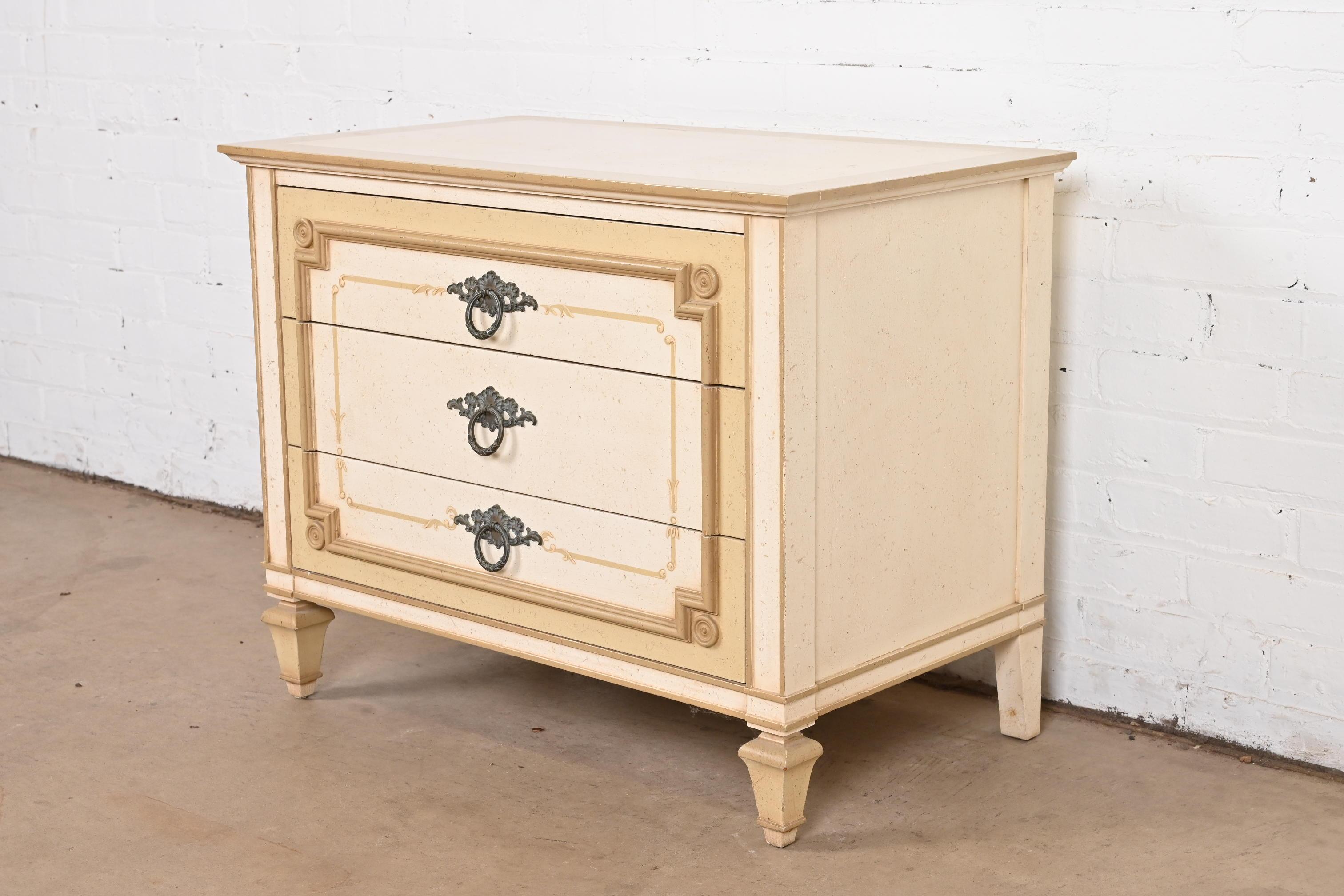 A gorgeous French Regency Louis XVI style painted three-drawer bachelor chest or bedside chest

By John Widdicomb

USA, Circa 1960s

Carved walnut in cream and taupe, with original brass hardware.

Measures: 30
