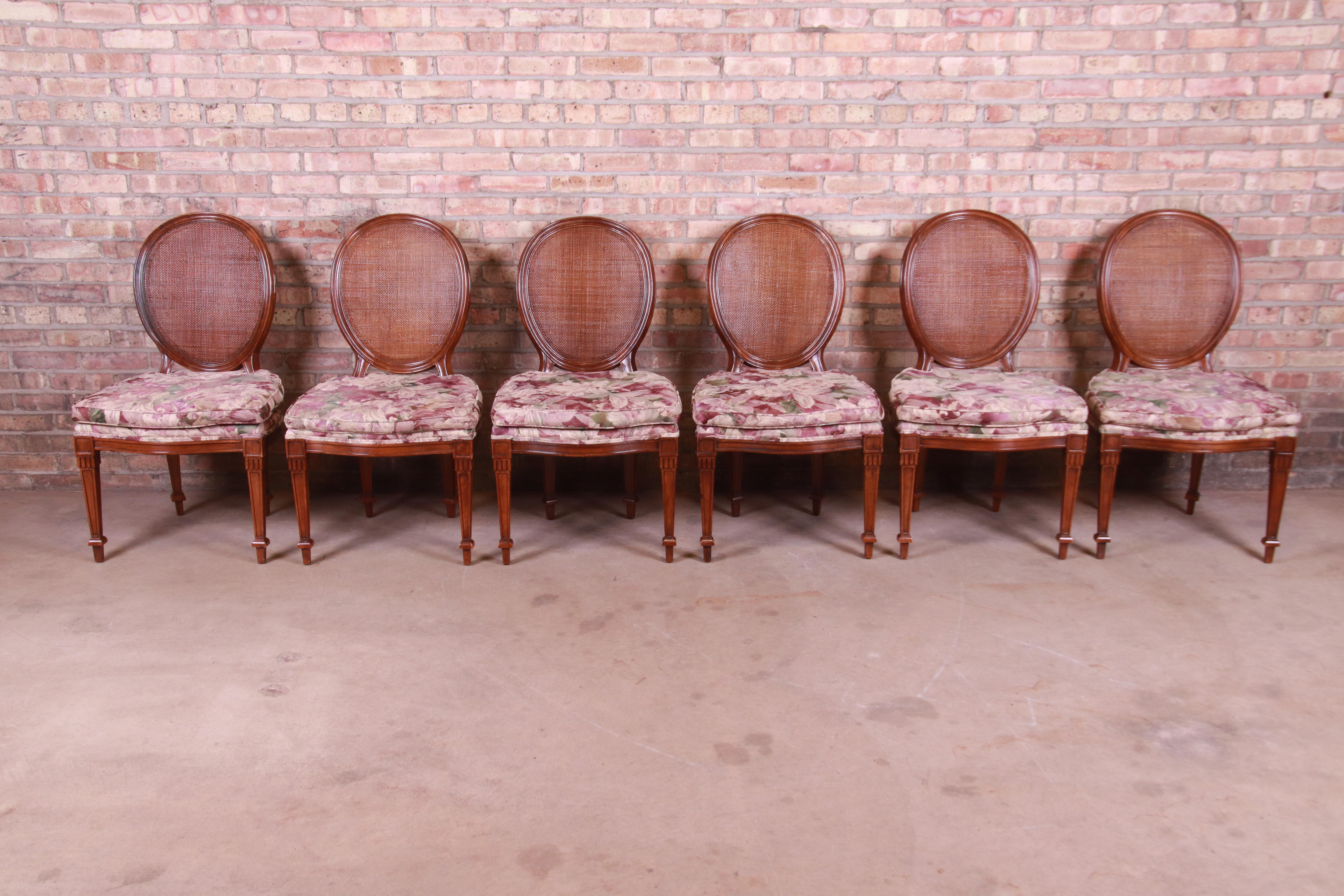 A gorgeous set of six French Regency style dining chairs

By John Widdicomb

USA, circa 1970s

Carved walnut, with floral upholstered seats and caned oval backs.

Measures: 21