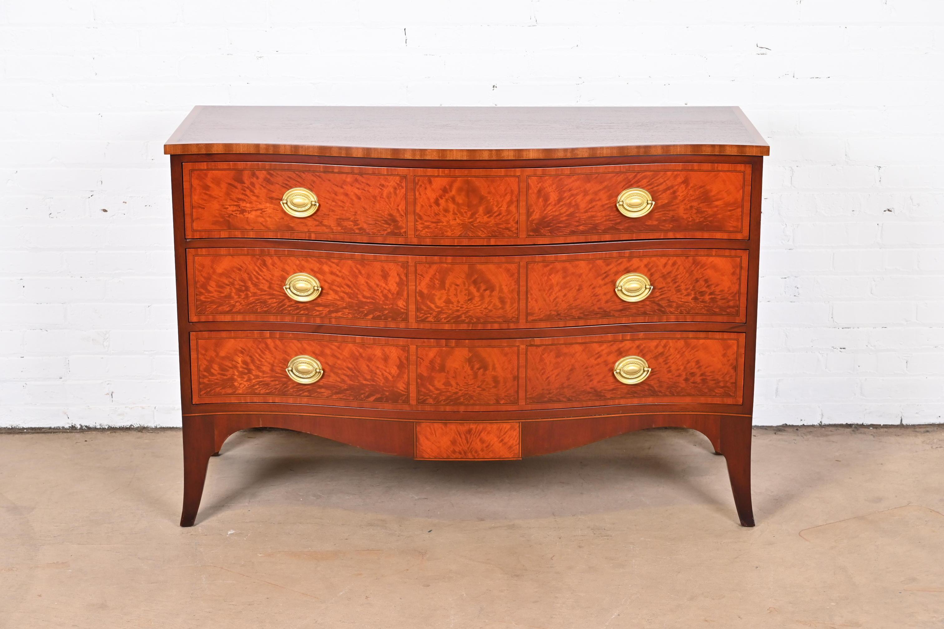 An exceptional Georgian style serpentine front commode or chest of drawers.

Designed by Ralph Widdicomb for John Widdicomb Co.

USA, Circa 1940s

Stunning book-matched flame mahogany, with satinwood inlay and original brass