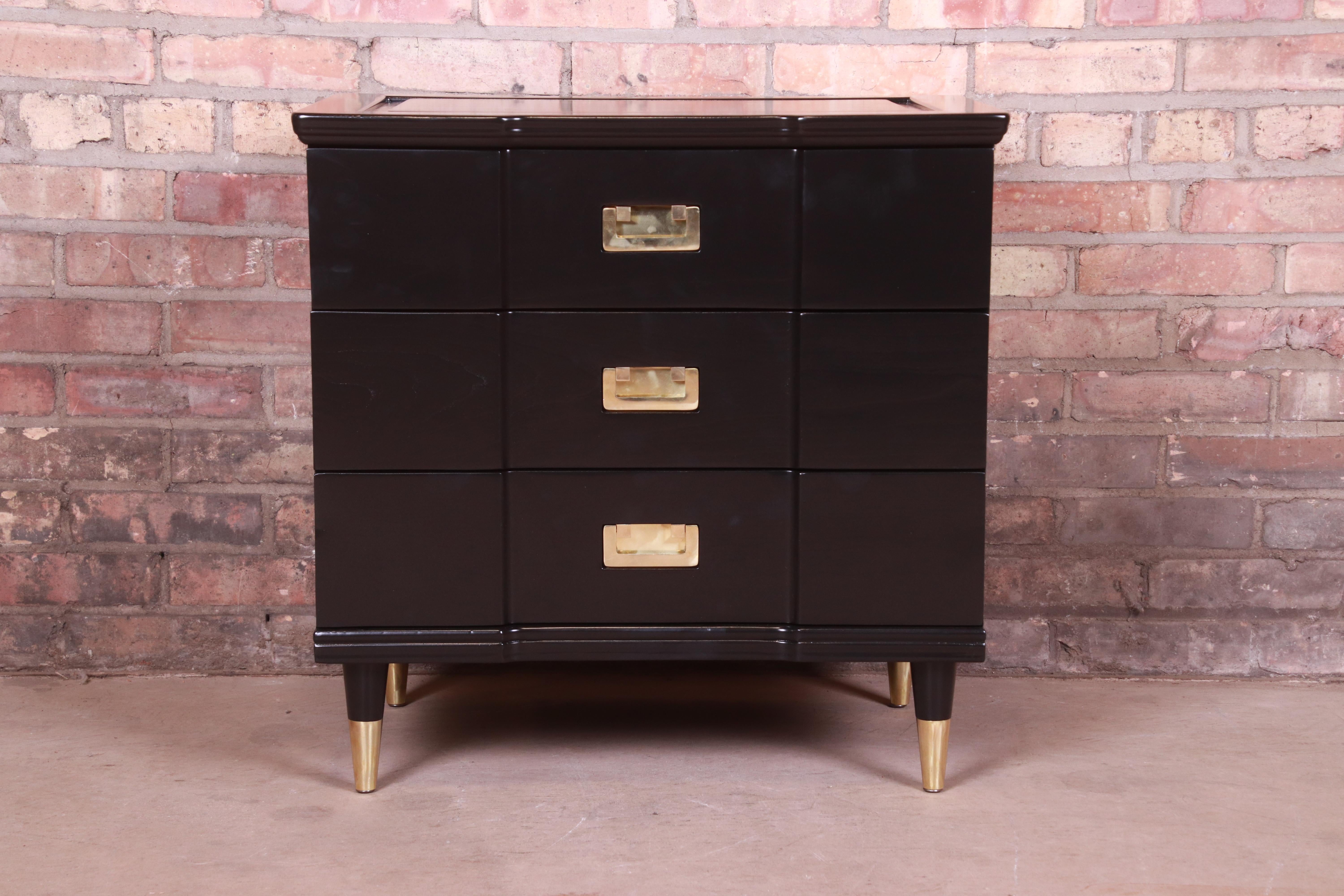 An exceptional Mid-Century Modern Hollywood Regency Campaign three-drawer bedside chest or bachelor chest

By John Widdicomb

USA, 1950s

Black lacquered solid cherry wood, with original brass hardware and brass-capped feet.

Measures: