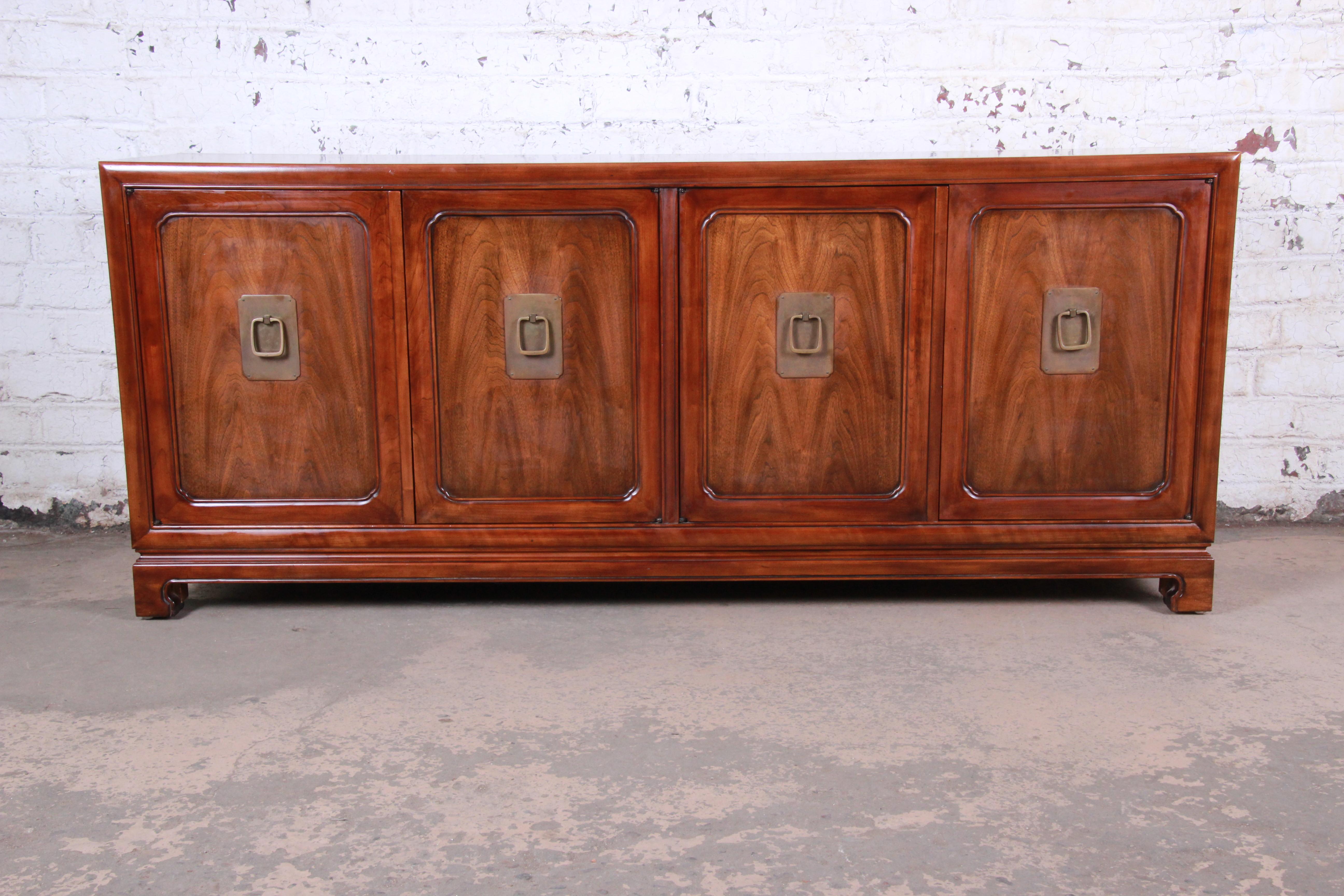 An exceptional Mid-Century Modern Hollywood Regency walnut sideboard or credenza

By John Widdicomb

USA, circa 1960s

Book-matched walnut and brass hardware and spring-loaded ball casters

Measures: 76.5