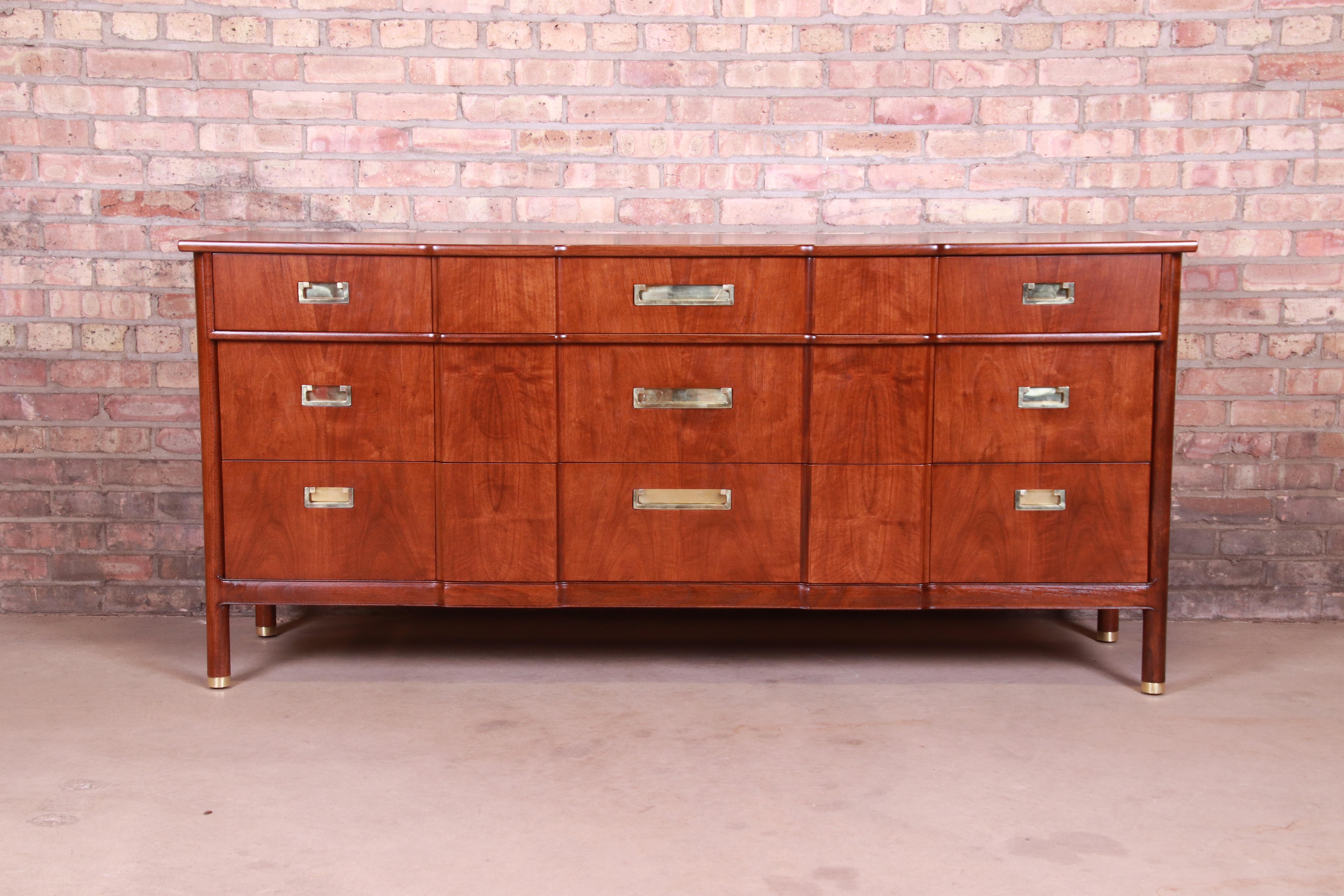 An exceptional Mid-Century Modern Hollywood Regency Campaign triple dresser or credenza

By John Widdicomb

USA, 1950s

Sculpted walnut, with original brass hardware and brass-capped feet.

Measures: 70