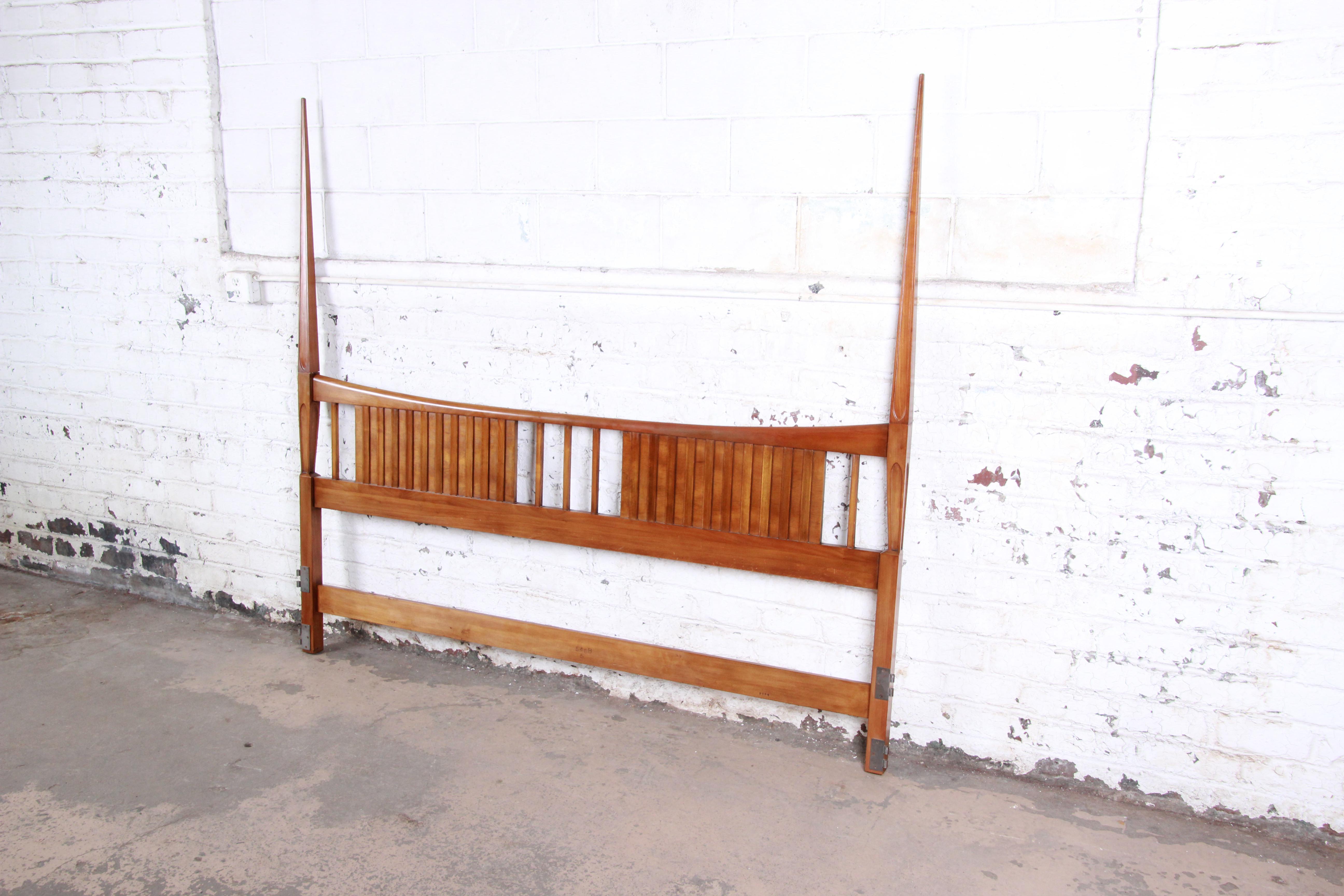 A gorgeous Mid-Century Modern sculpted cherrywood king size headboard by John Widdicomb. The headboard features gorgeous wood grain and sleek mid-century design, with tall tapered posts. The original label is present. The headboard is in excellent