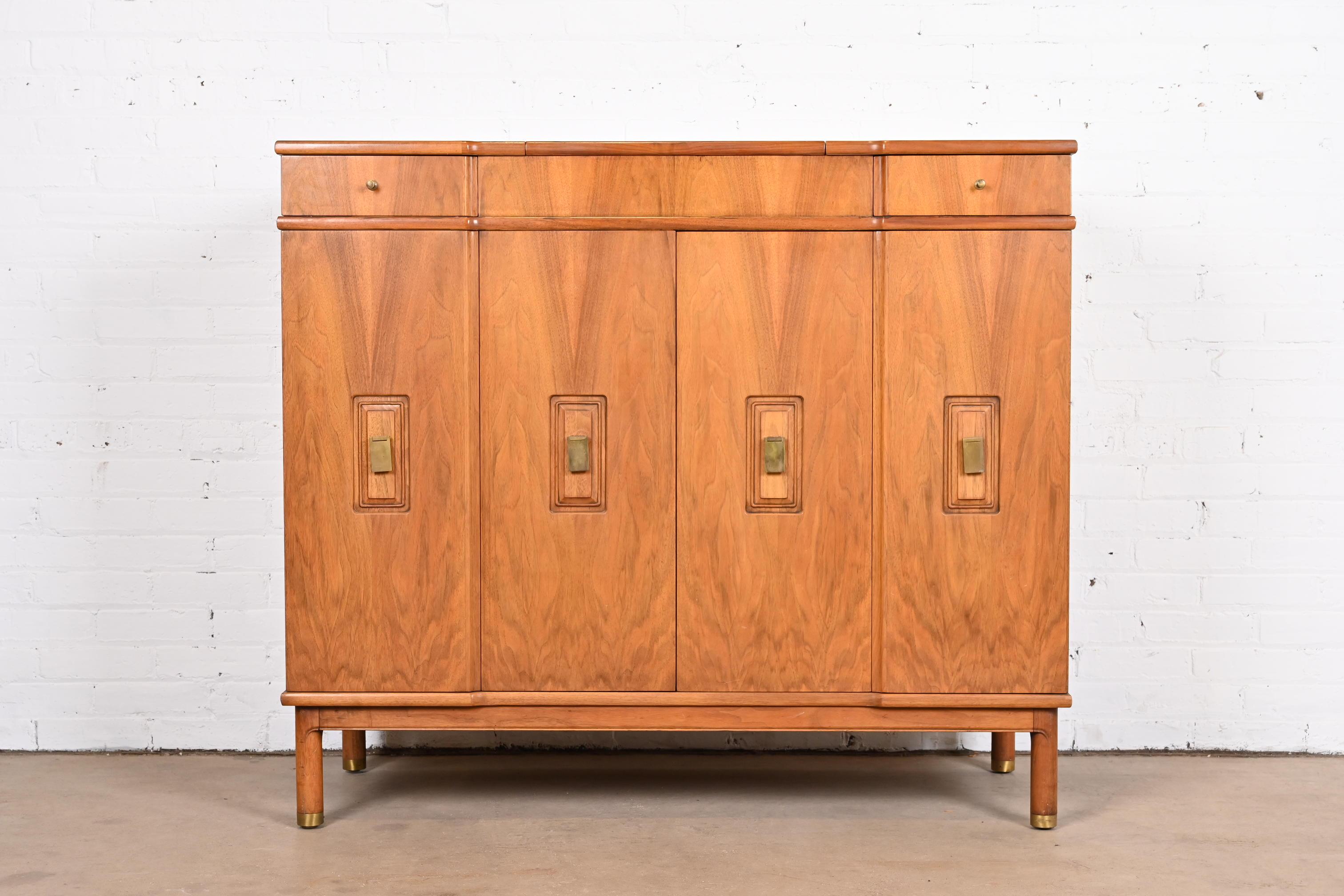 An exceptional Mid-Century Modern ten-drawer gentleman's chest with flip up mirror

By John Widdicomb

USA, Circa 1960s

Gorgeous book-matched walnut, with original brass hardware and brass-capped feet.

Measures: 48