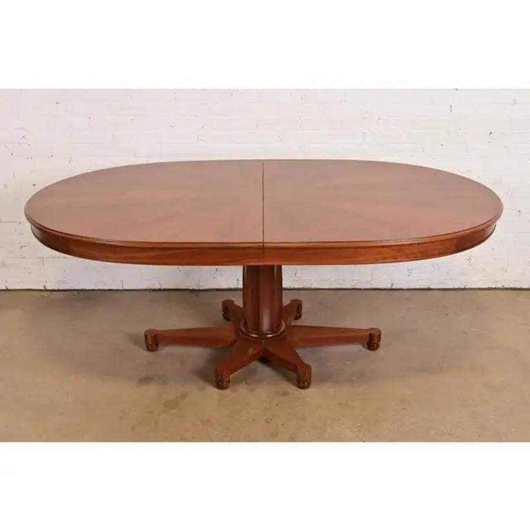A gorgeous mid-century Regency or Neoclassical style pedestal extension dining table

Attributed to John Widdicomb

USA, Circa 1960s

Cherry wood, with beautiful book-matched starburst pattern on top.

Measures: 77.75