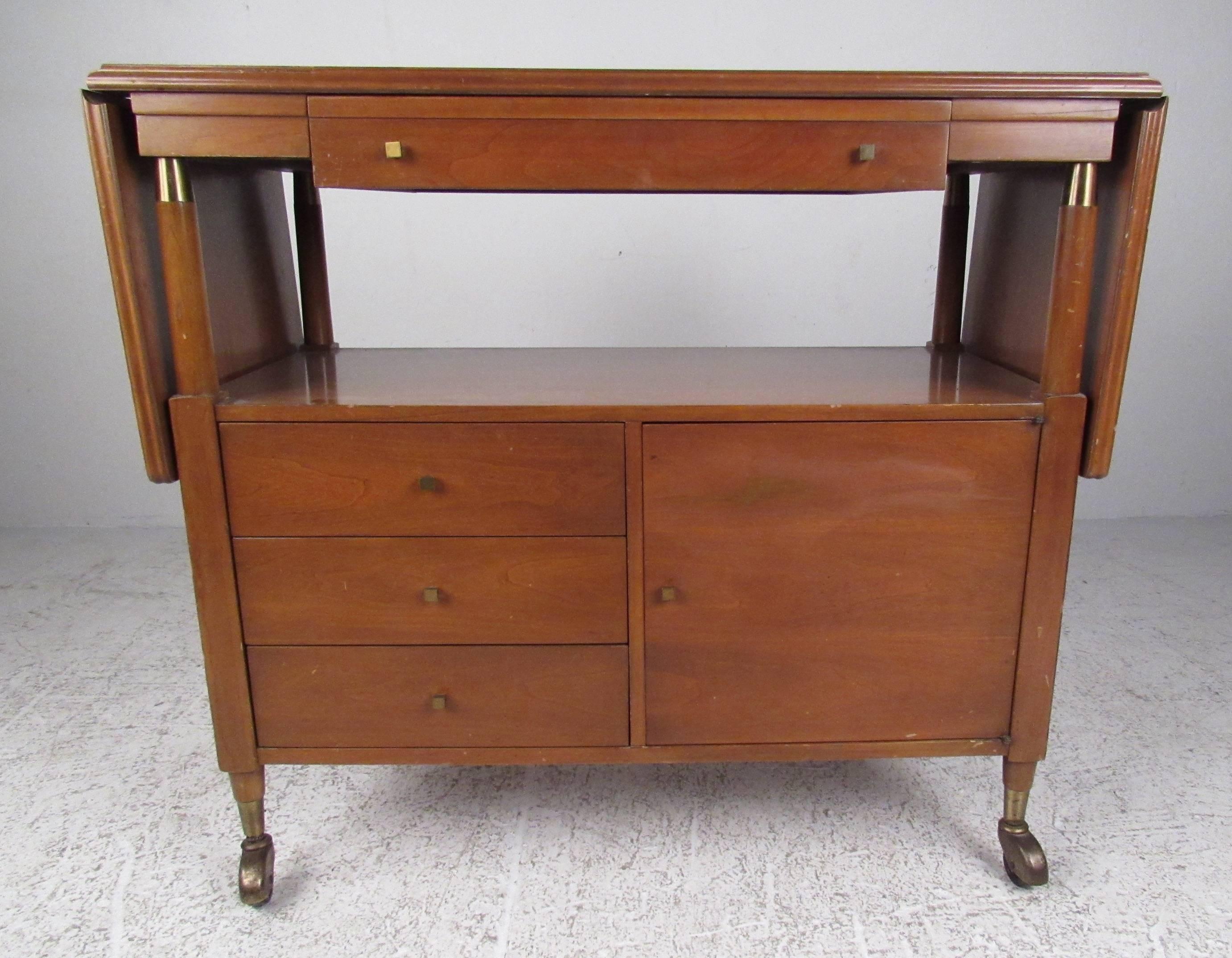 Nicely designed compact bar cart with ample storage options and extension leaves on both sides. A vintage modern piece with a rich walnut finish and unique brass pulls. Please confirm the item location (NY or NJ) with dealer.

Leaves open: 64 inches