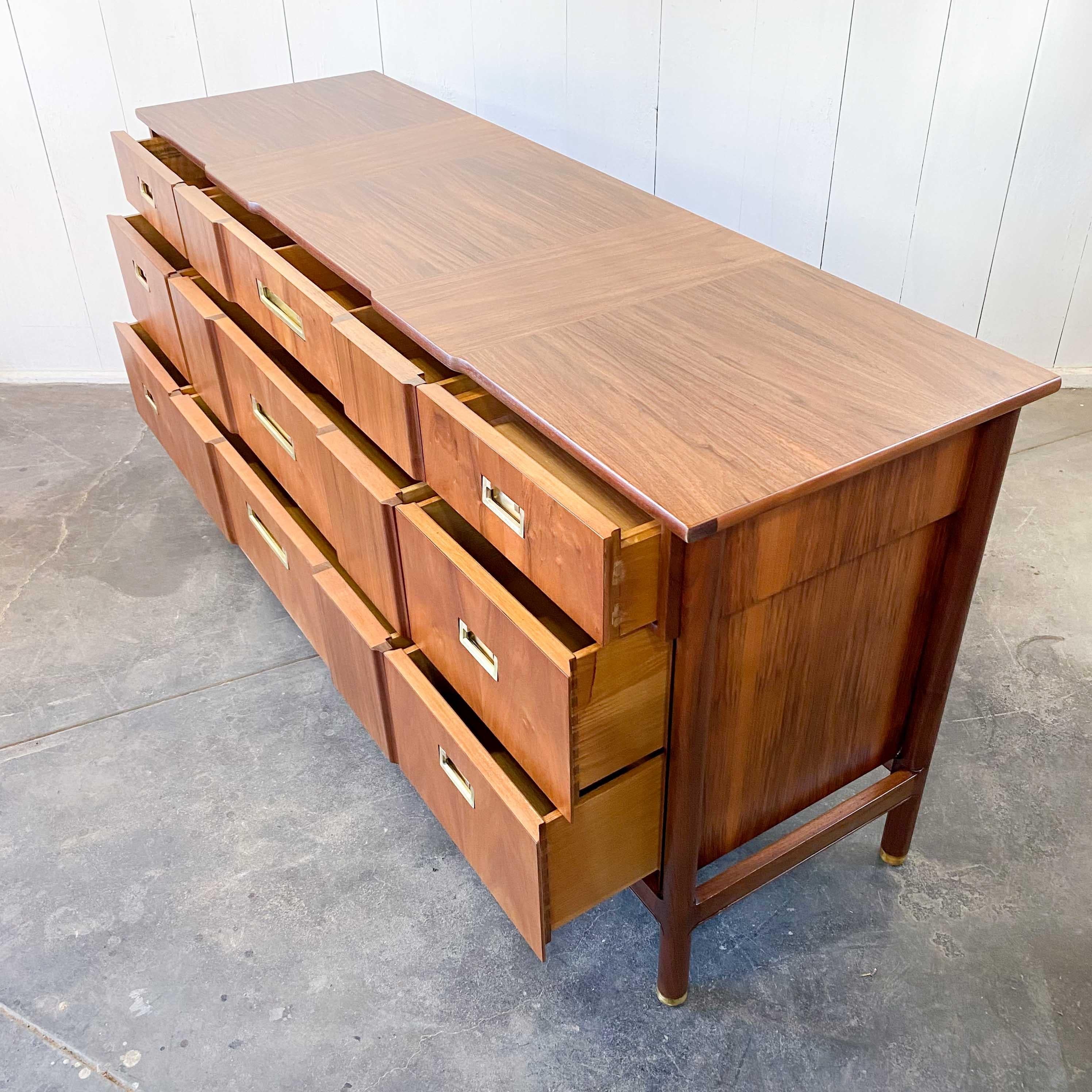Nine drawer dresser designed by J. Stuart Clingman for John Widdicomb Co. prior to his death in 1956.
Quarter-cut rosewood framing, sculpted facia, over hanging top drawers, book matched rosewood veneer with cut back side panels, brass sabots and