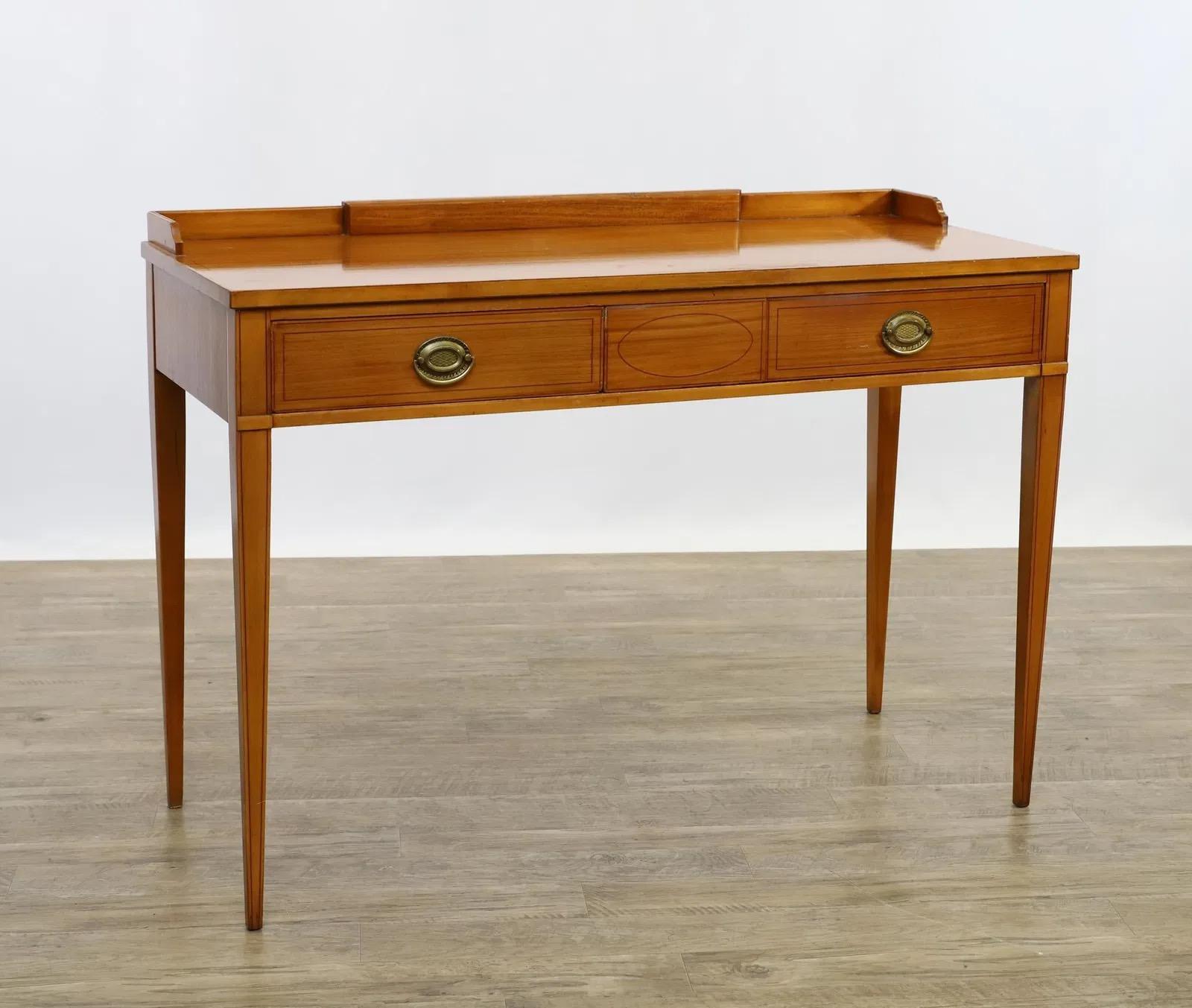 Mid-20th-century John Widdicomb vanity in satinwood veneer with banded inlay, featuring a backsplash and two drawers on tapered legs. Vanity dimensions are 30 inches high, 44 inches wide, and 18 inches deep. Paired with a rectangular cheval mirror