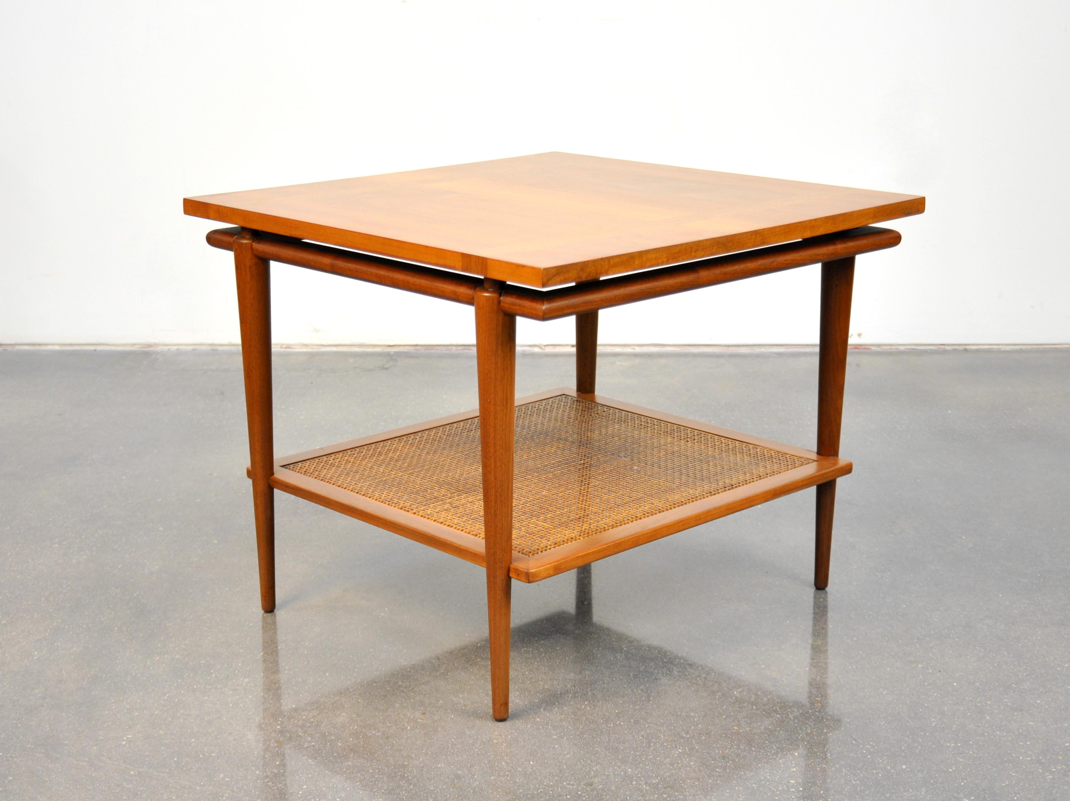 A vintage 1960s Mid-Century Modern end table with floating top and caning by John Widdicomb. The professionally refinished occasional table features a square top floating over a base with tapering legs and a caned magazine shelf. Works well with