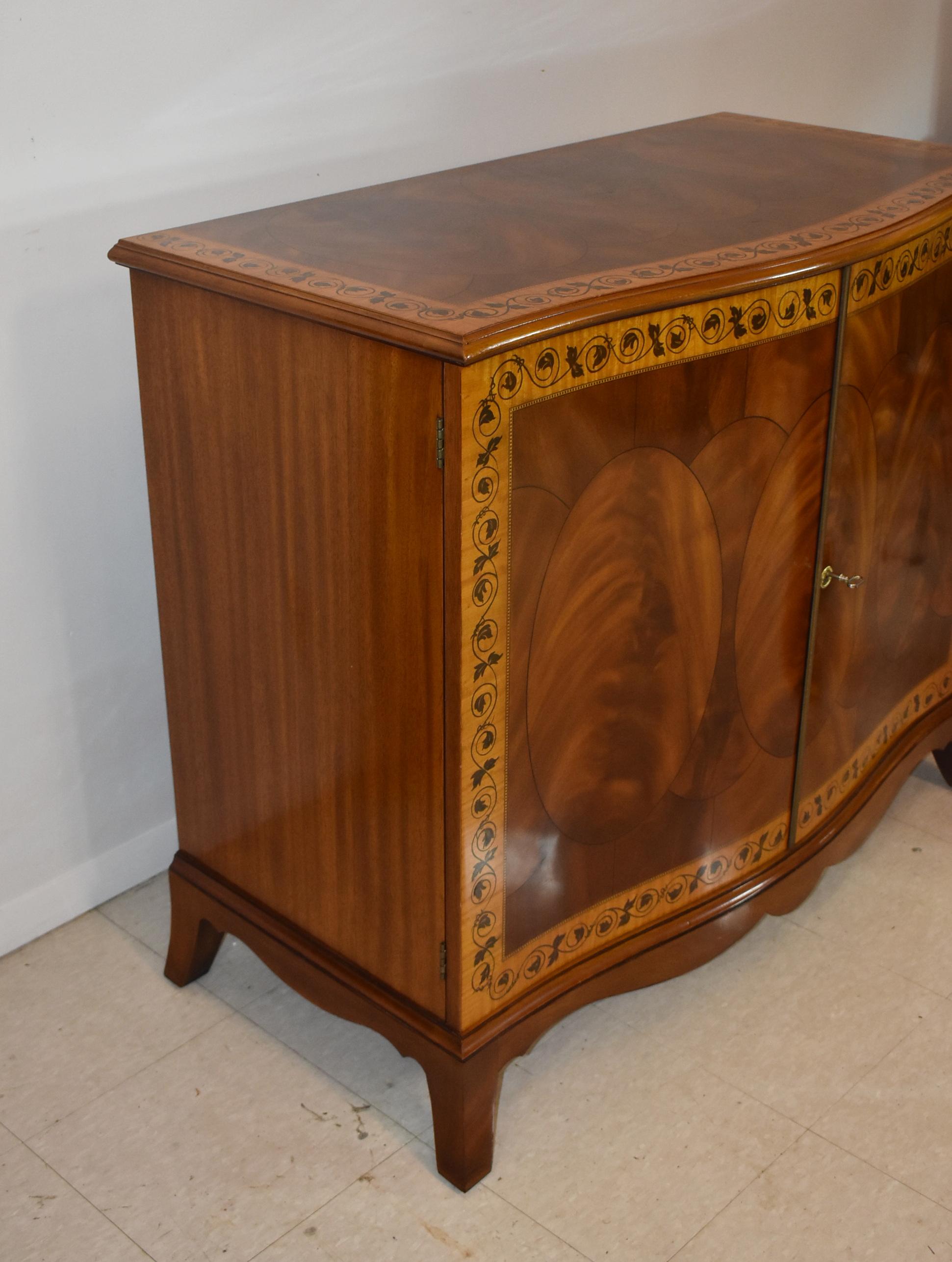 Mobile server in noce John Widdicomb con bordo in legno di raso e mogano decorato con un disegno di viti e foglie. L'armadio è dotato di 2 ante con un ripiano interno e 2 cassetti, e ha una base a staffa ritagliata. Eccellenti condizioni vintage,