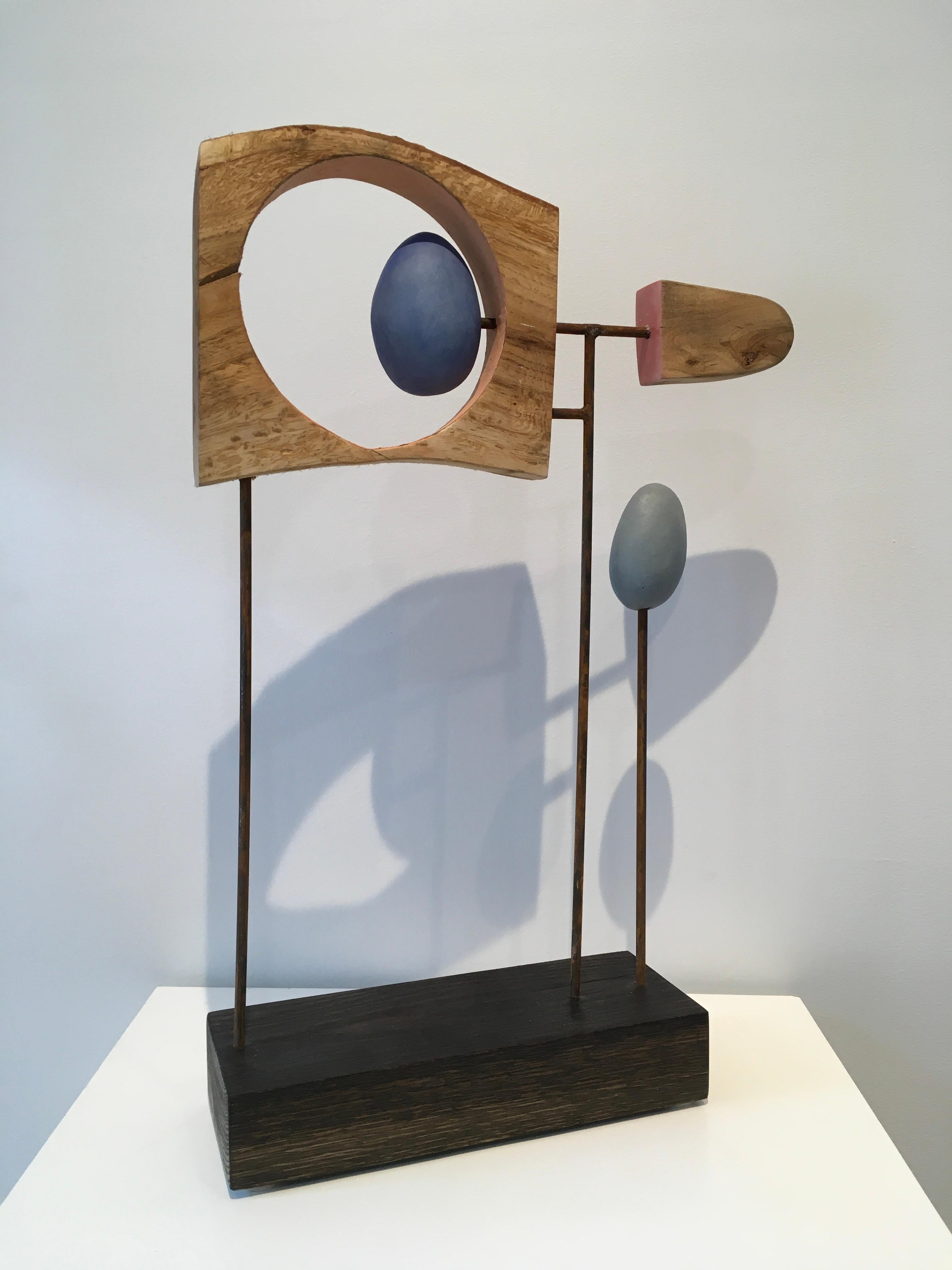John Wolfes abstrakte Mixed-Media-Skulptur "Untitled Assemblage #S 3-23" vereint Holz, Stahl, Keramikelemente und Acrylfarbe. Die warmen Farben des Holzes und der bemalten Keramikelemente lockern die geradlinige Anordnung auf. Die geringe Tiefe der