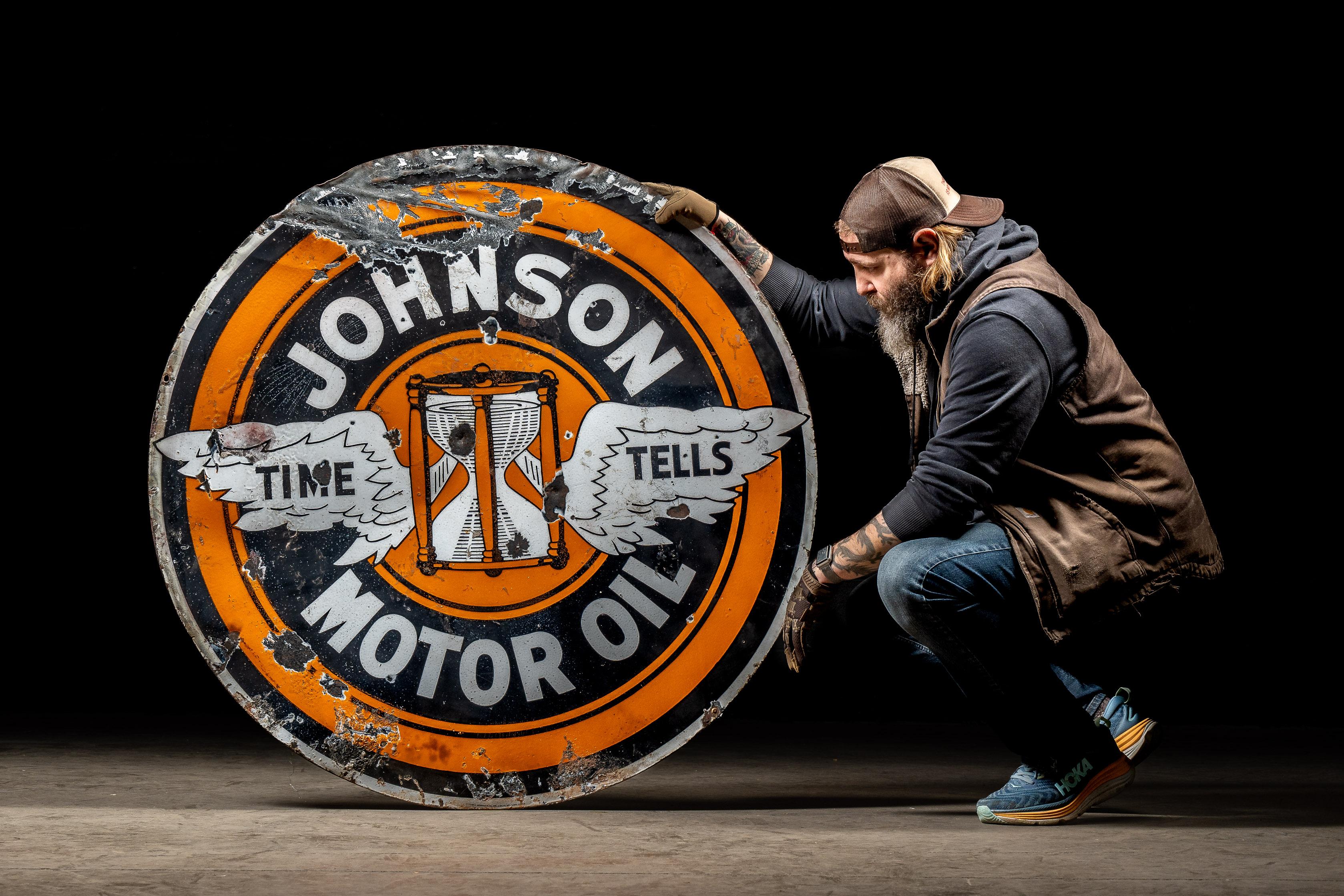 Este cartel anuncia Gasolina Johnson (estilísticamente escrita de forma errónea) vendida con compuesto antidetonante etilo. Johnson era conocido no sólo por esta marca, sino por otras bajo su bandera, como Brilliant Bronze y Jo-Re-Co. Johnson era