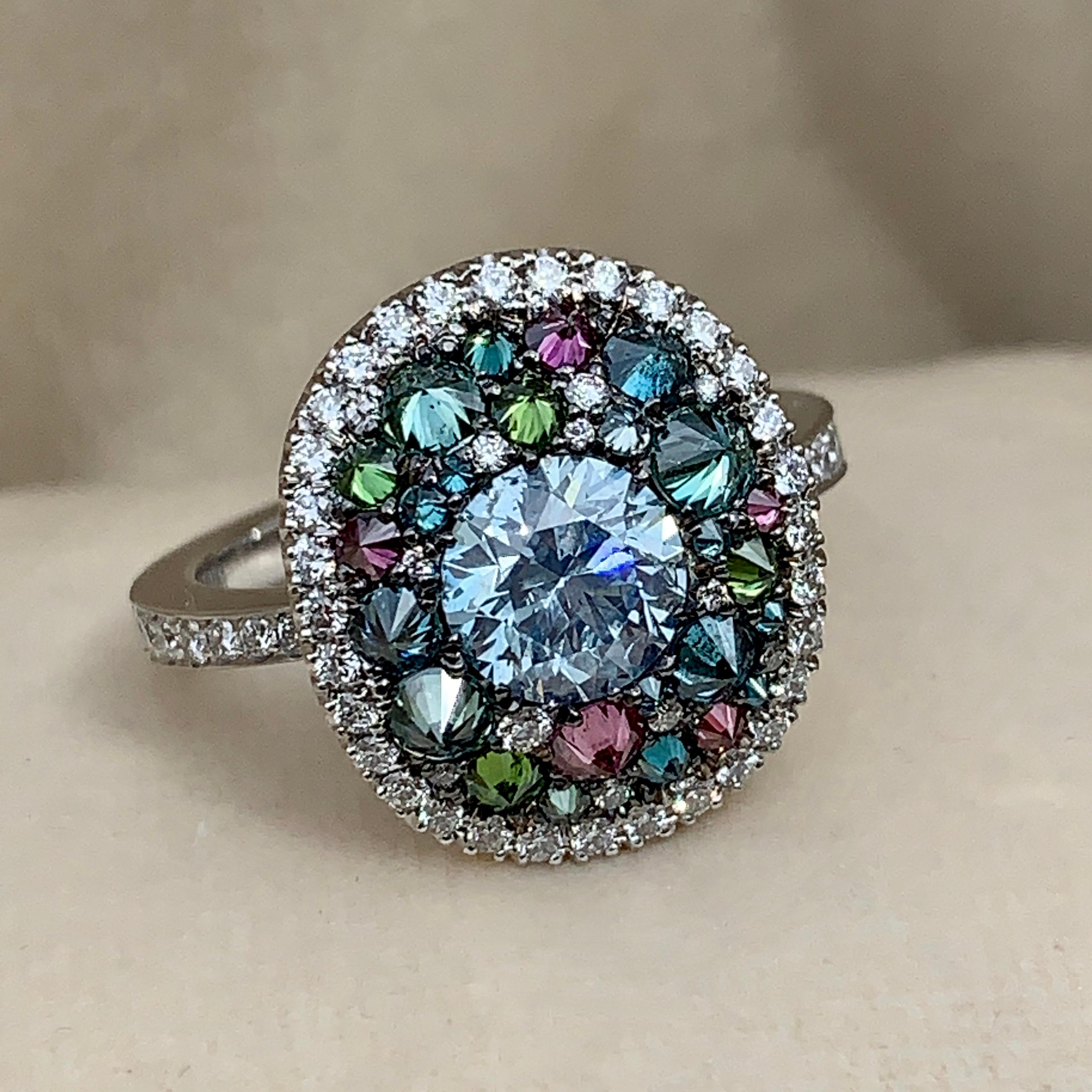 One of a kind ring in 18K White gold 6,9 g set with a natural coloured blue diamond centerstone 1,07 carat., white DEGVVS diamonds, Upside down set natural coloured Blue, green & purple diamonds 1,42 ct. Total diamonds: 2,49 carat.
Size EU 53 US 6,3