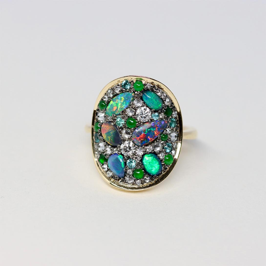 Discover the beauty and precision of Belgian craftsmanship in this one-of-a-kind ring by jewellery designer Joke Quick, featuring mesmerising black opals from Lightning Ridge, Australia, vivid Paraiba tourmalines, top-quality Type A jadeite, and