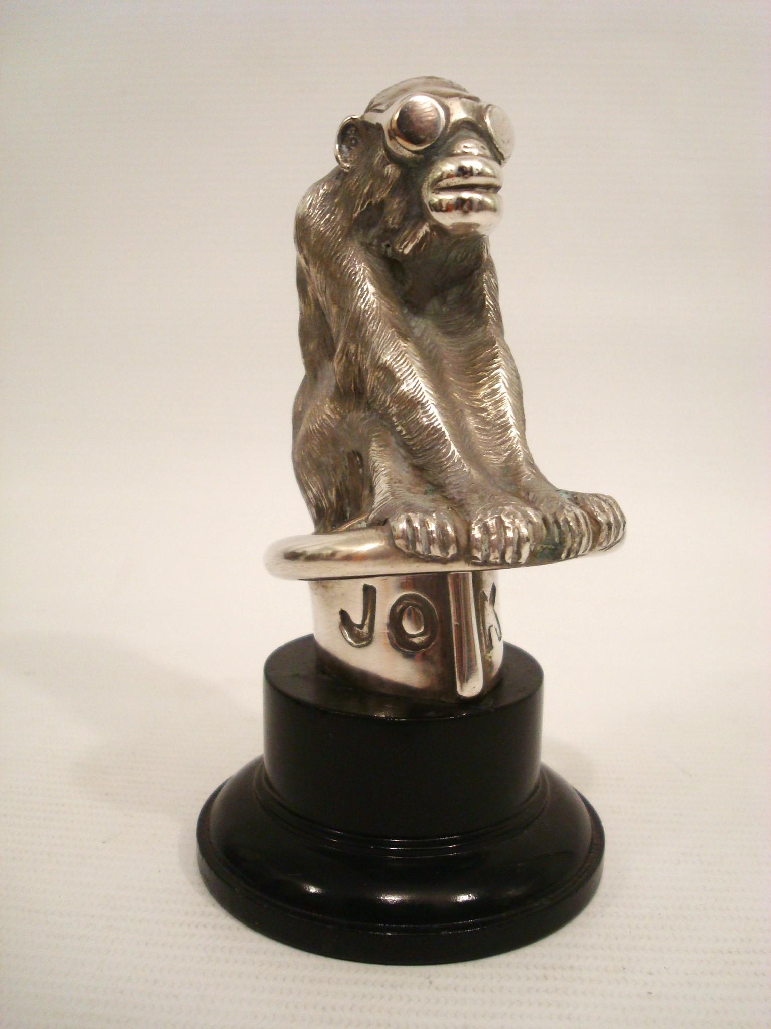 Very Rare art deco english silver plated bronze sculpture figure of a driving  Monkey, Car Mascot / Hood Ornament / Desk Paperweight.
Inscribed JOKO on the front and L. Brunswick on the back.

A sculpture or figurine of a monkey wearing goggles. The