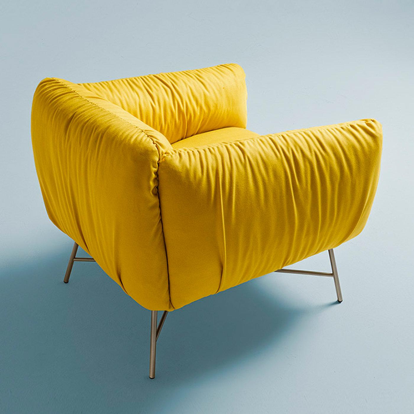 Perfect for setting a joyful tone in dull decors, this armchair is the perfect synthesis of plushness and vibrancy. A distinctive interplay of solids and voids defines its volumes, where the ultra-thin cylindrical elements in champagne-finished