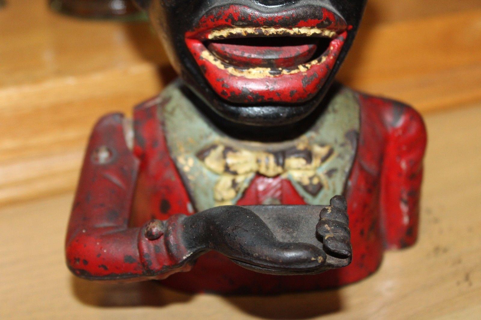 This black Americana coin bank is stamped made in England and is made out of cast iron. Insert a penny in his hand and push lever down located behind his arm. That will bring his other arm up and puts the penny inside his mouth.