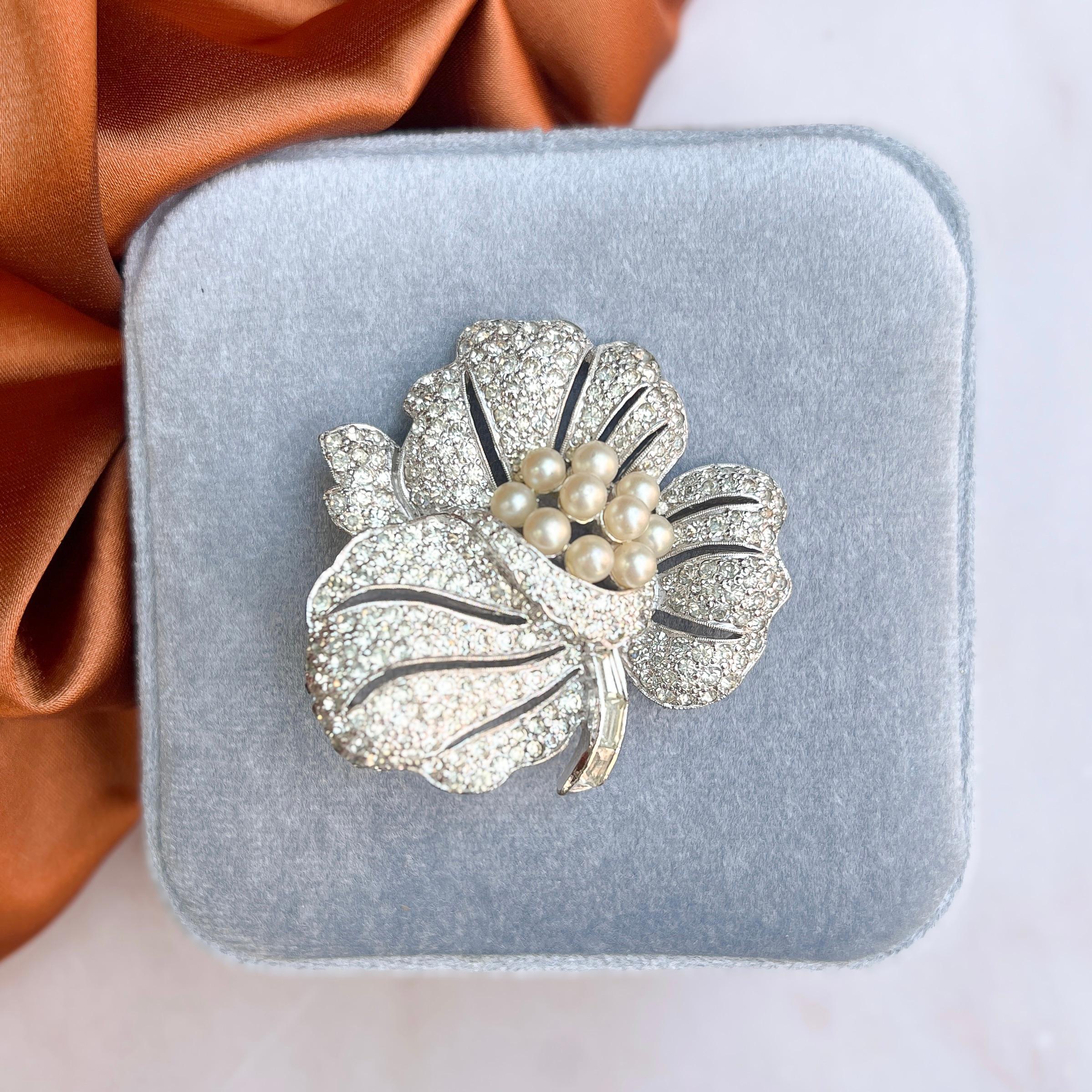 This timeless brooch was created in the 1950s by the American Jomaz company. 

Condition Report:
Excellent

The Details...
This brooch is constructed from rhodium plated metal. It features a flower motif and is accented with small, round and